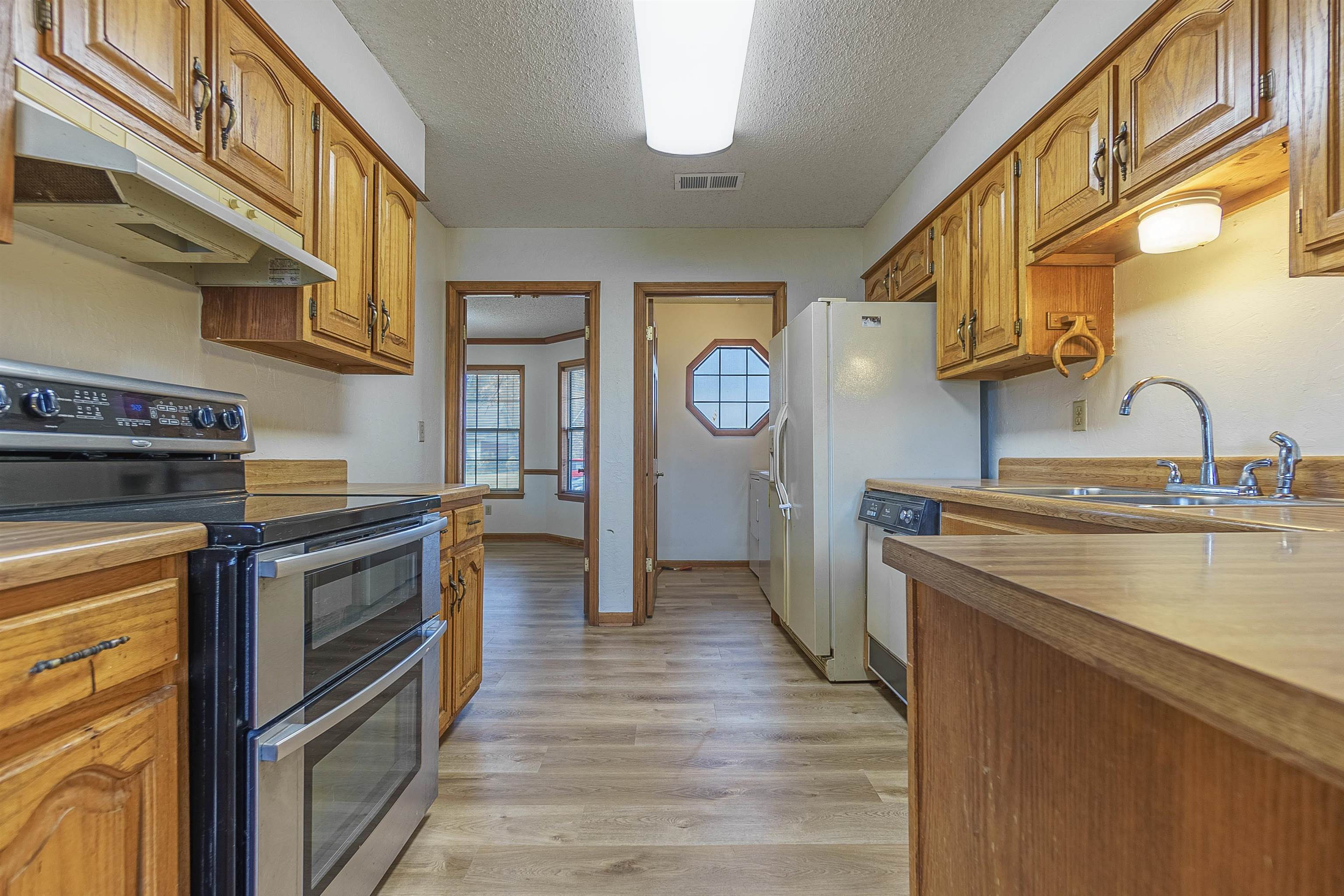 Kitchen featuring sink, light hardwood / wood-style flooring, white dishwasher, double oven range, and a textured ceiling