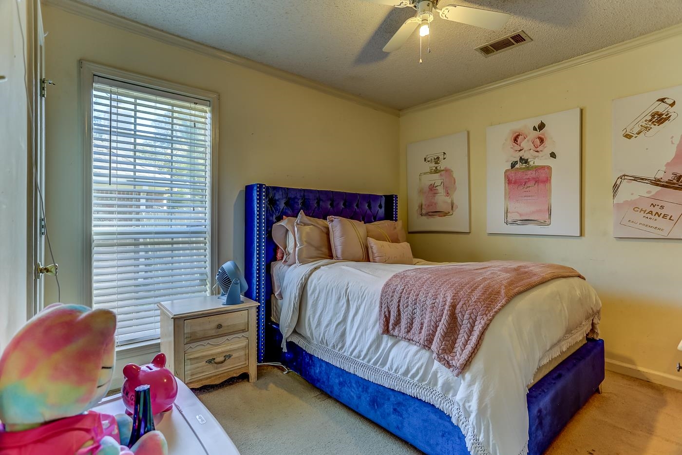 Carpeted bedroom featuring ceiling fan, ornamental molding, and a textured ceiling