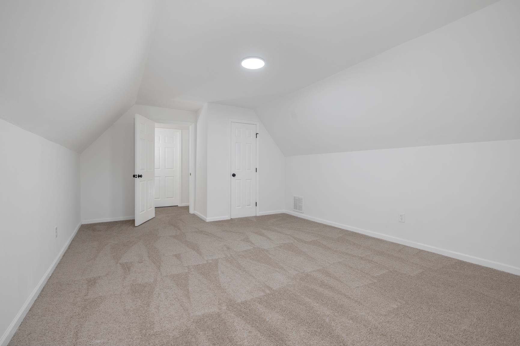 Additional living space featuring light colored carpet and lofted ceiling