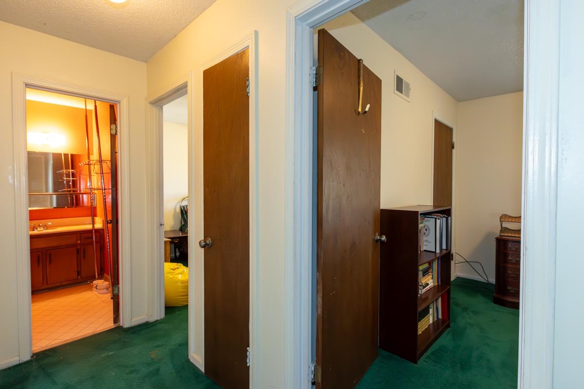 Hallway with dark colored carpet and a textured ceiling