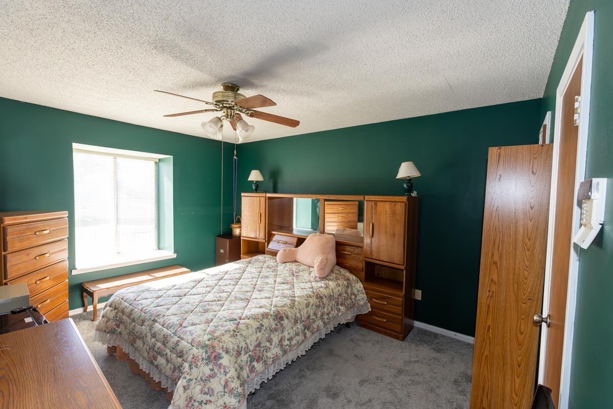 Bedroom featuring carpet, ceiling fan, and a textured ceiling