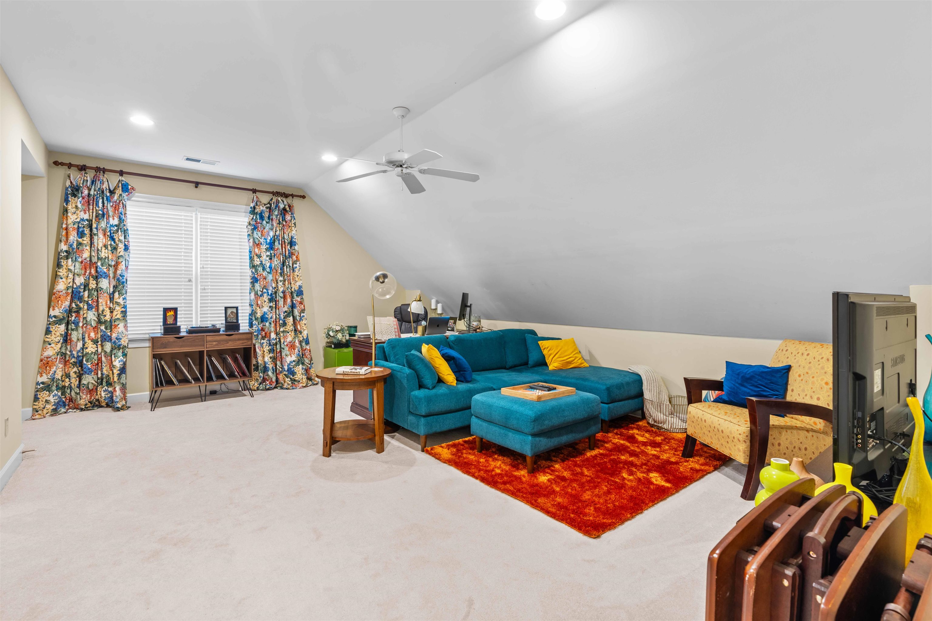 Carpeted living room featuring ceiling fan and lofted ceiling