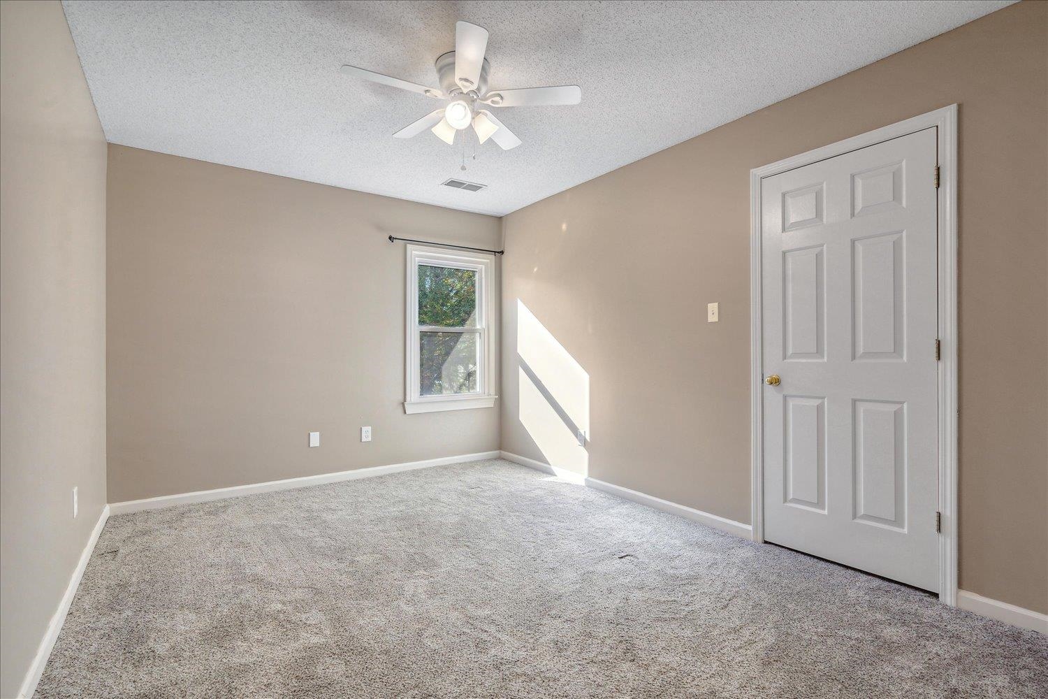 Carpeted spare room featuring ceiling fan and a textured ceiling