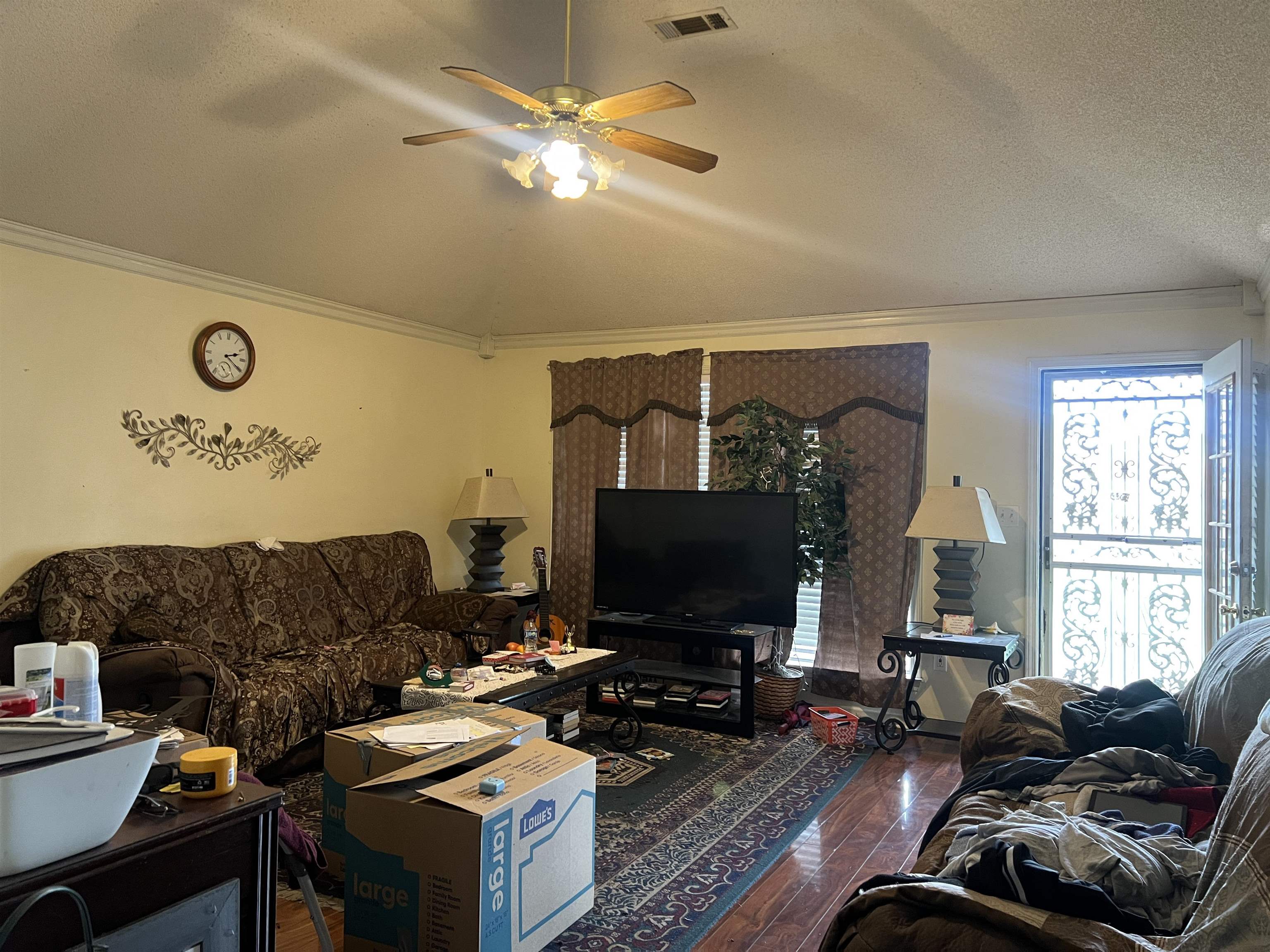 Living room featuring a textured ceiling, crown molding, ceiling fan, and dark wood-type flooring