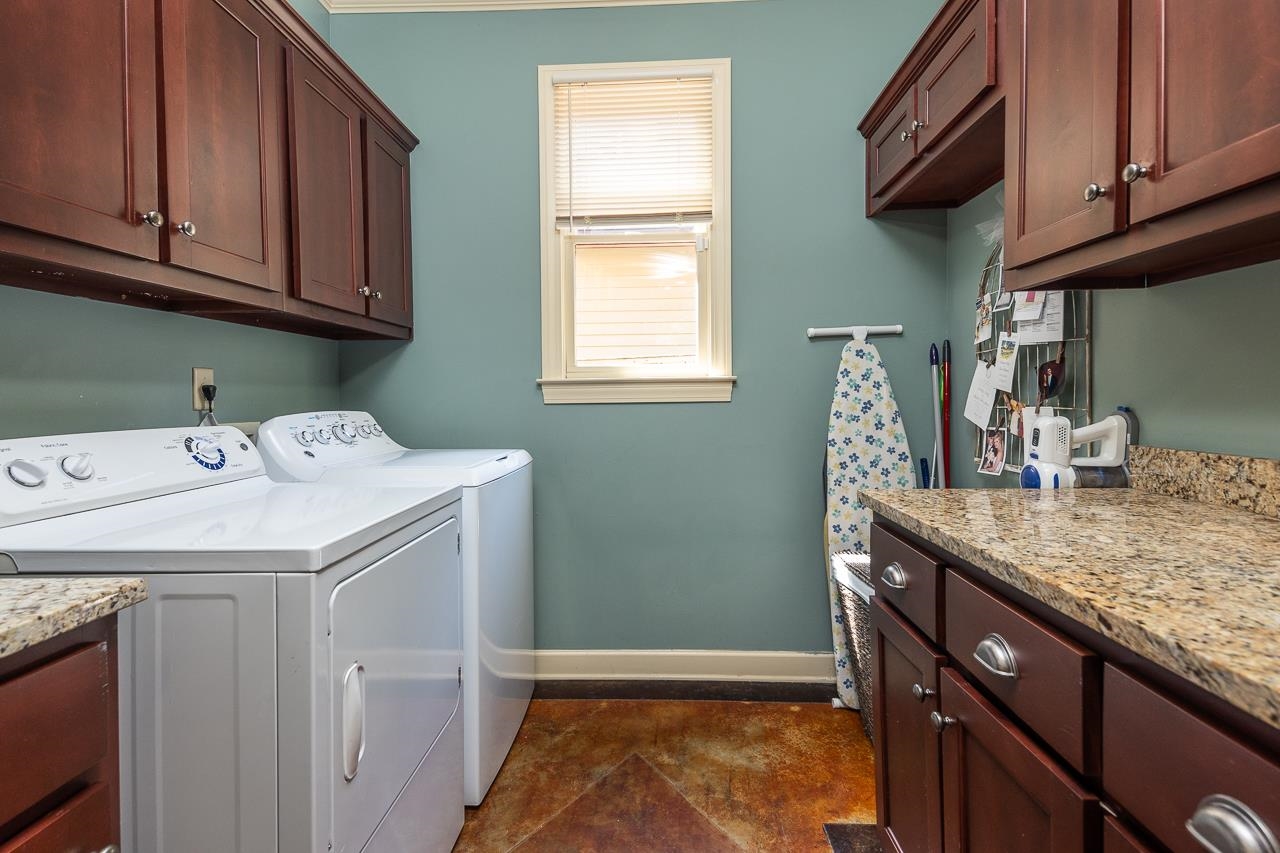 Laundry area featuring dark tile patterned flooring, cabinets, and washing machine and clothes dryer