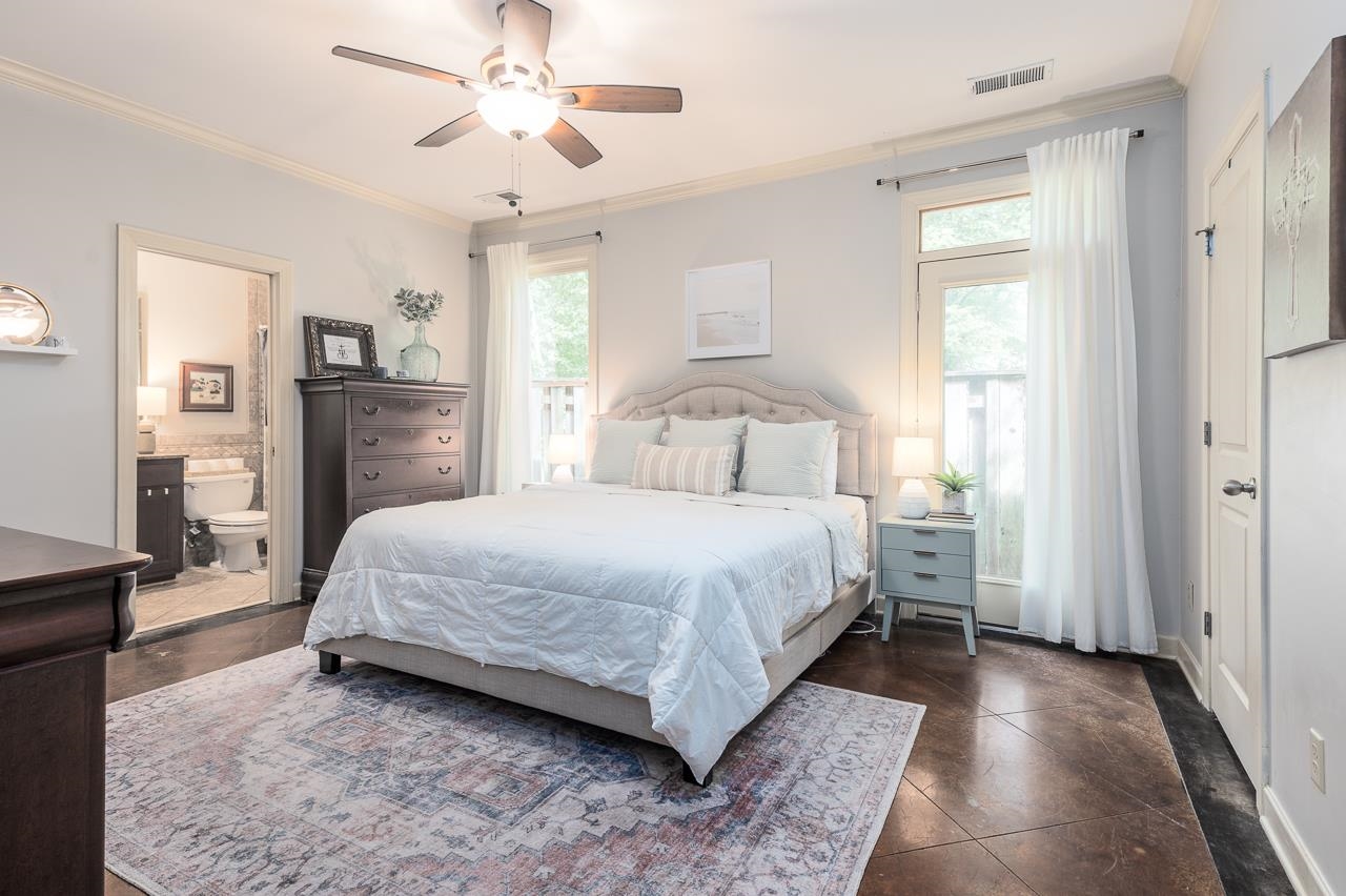 Bedroom with dark tile patterned floors, ceiling fan, ensuite bathroom, and crown molding