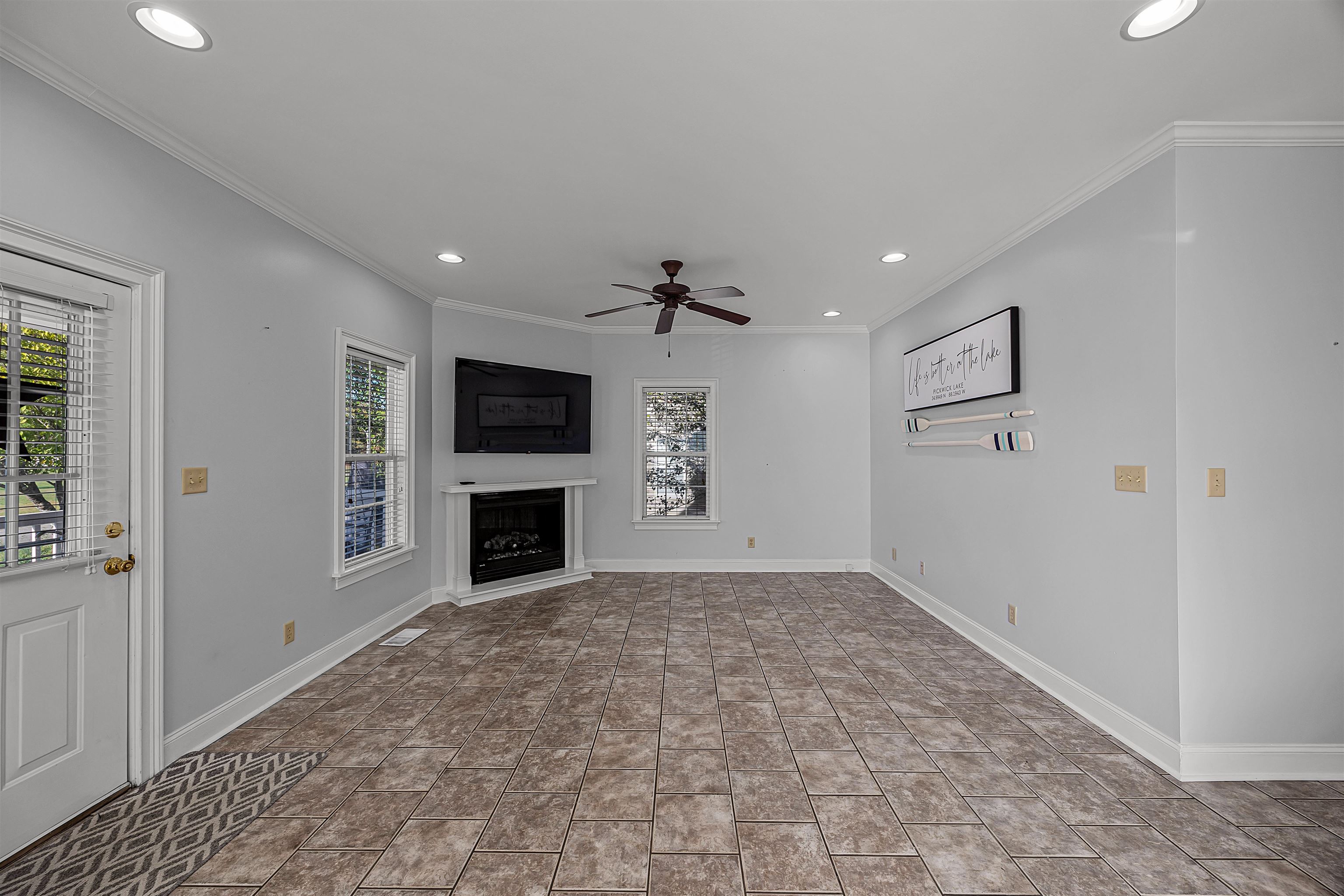 Unfurnished living room with ceiling fan and crown molding