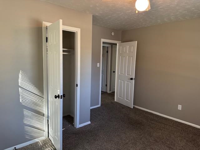 Unfurnished bedroom featuring a closet, dark carpet, and a textured ceiling