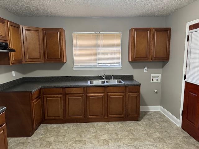 Kitchen featuring ventilation hood, sink, and a textured ceiling