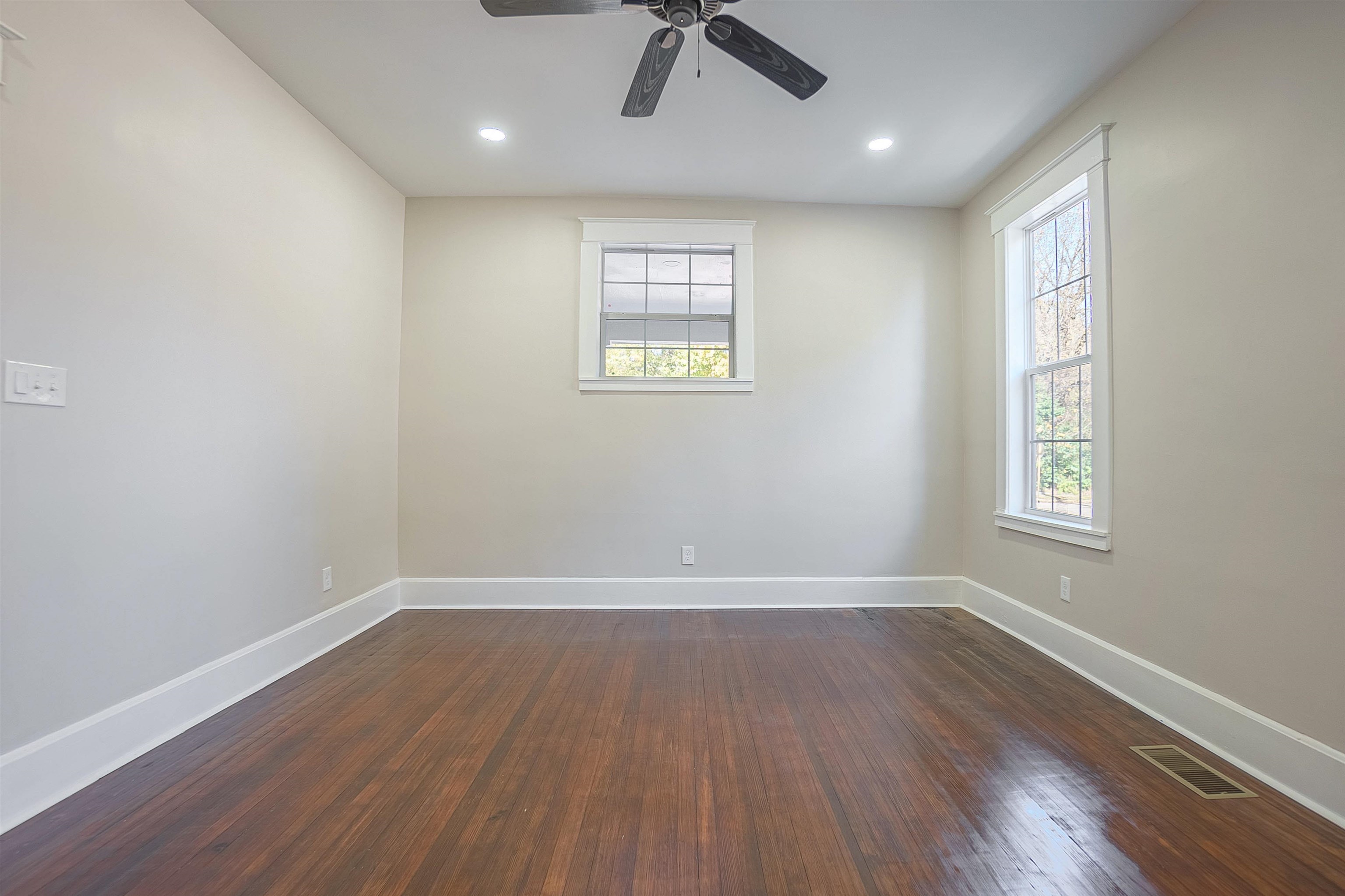 Empty room with ceiling fan and dark wood-type flooring