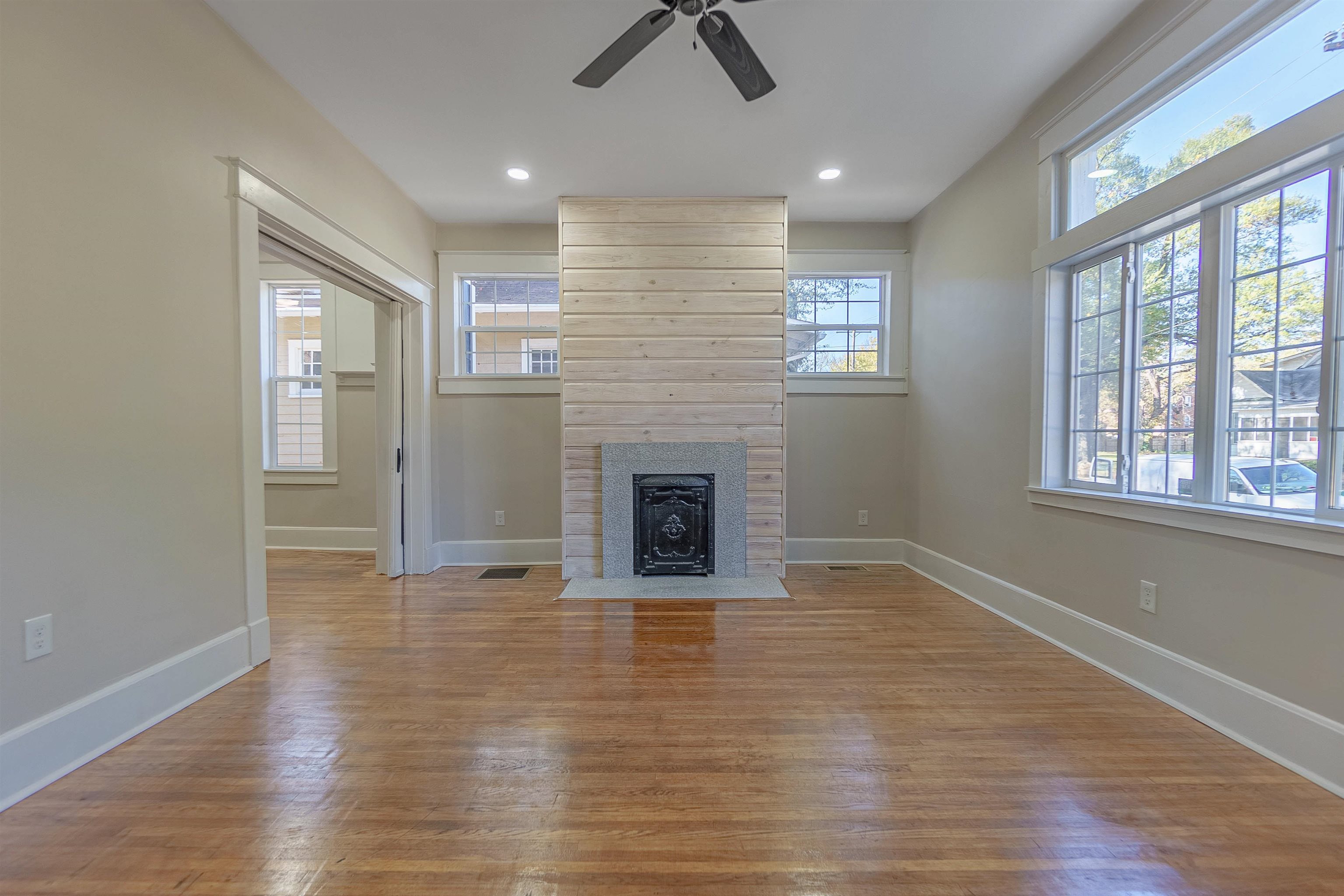Unfurnished living room with hardwood / wood-style flooring, ceiling fan, and a tiled fireplace