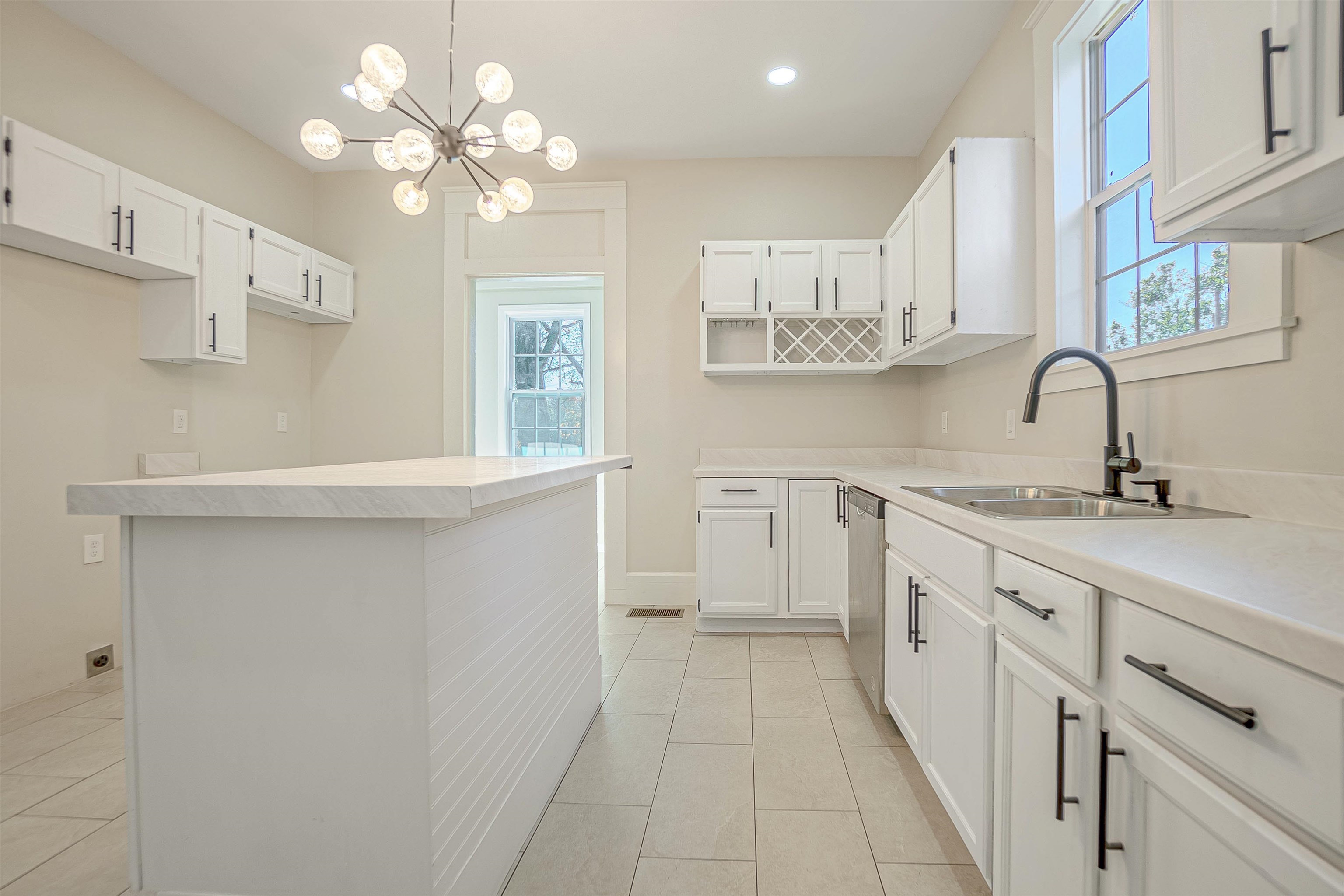 Kitchen featuring pendant lighting, white cabinetry, sink, and an inviting chandelier