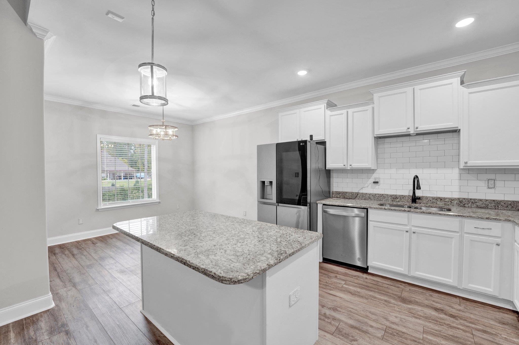 Kitchen featuring a center island, sink, light hardwood / wood-style flooring, white cabinets, and appliances with stainless steel finishes