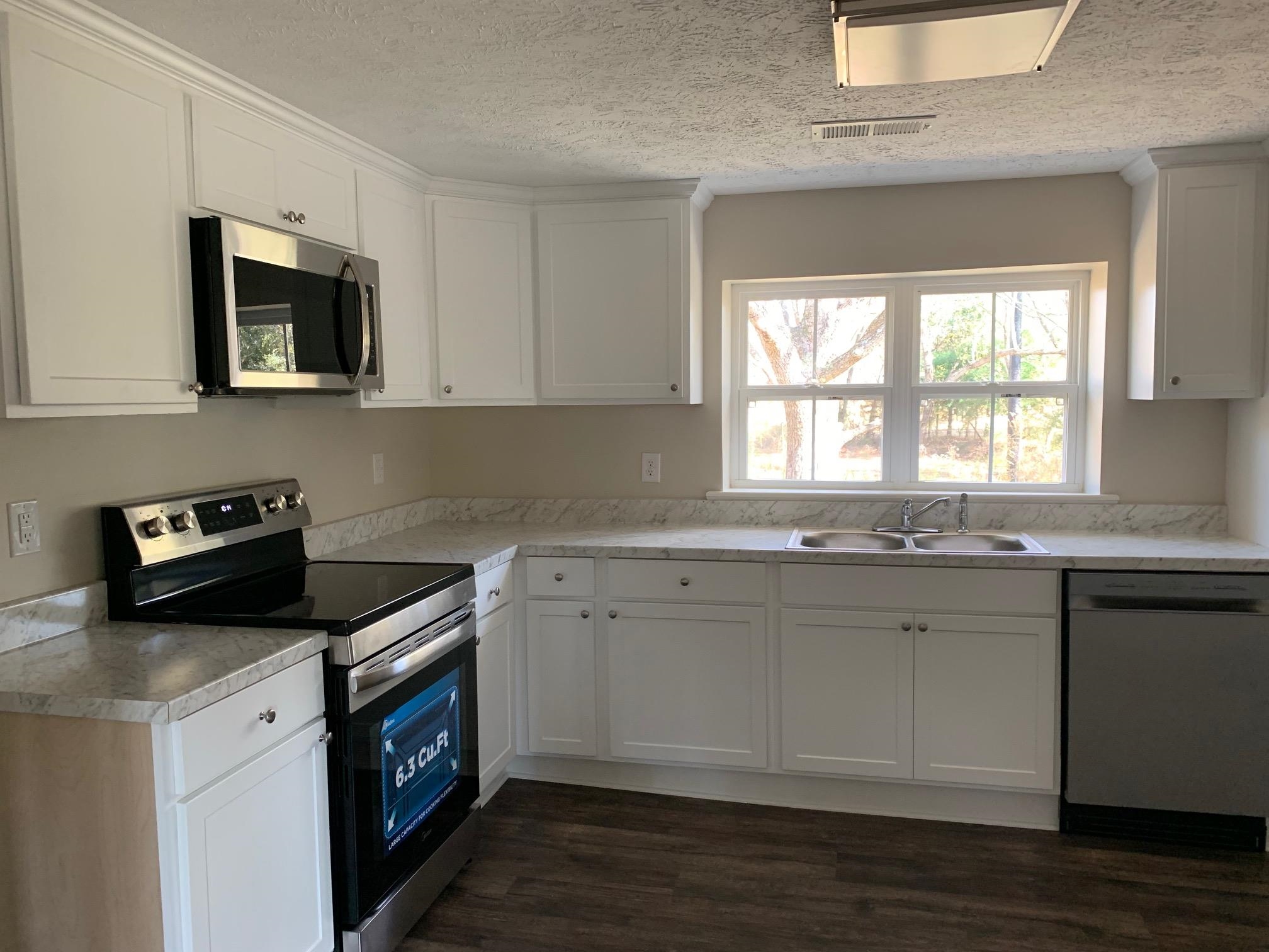 Kitchen with dark wood-type flooring, white cabinets, sink, a textured ceiling, and stainless steel appliances