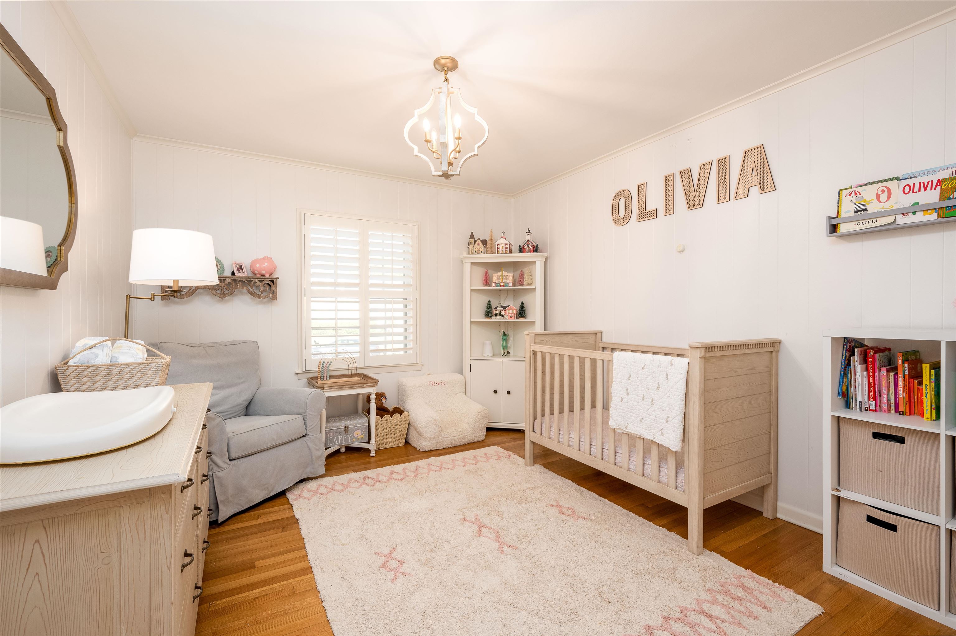 Bedroom featuring light hardwood / wood-style floors, an inviting chandelier, a nursery area, and crown molding