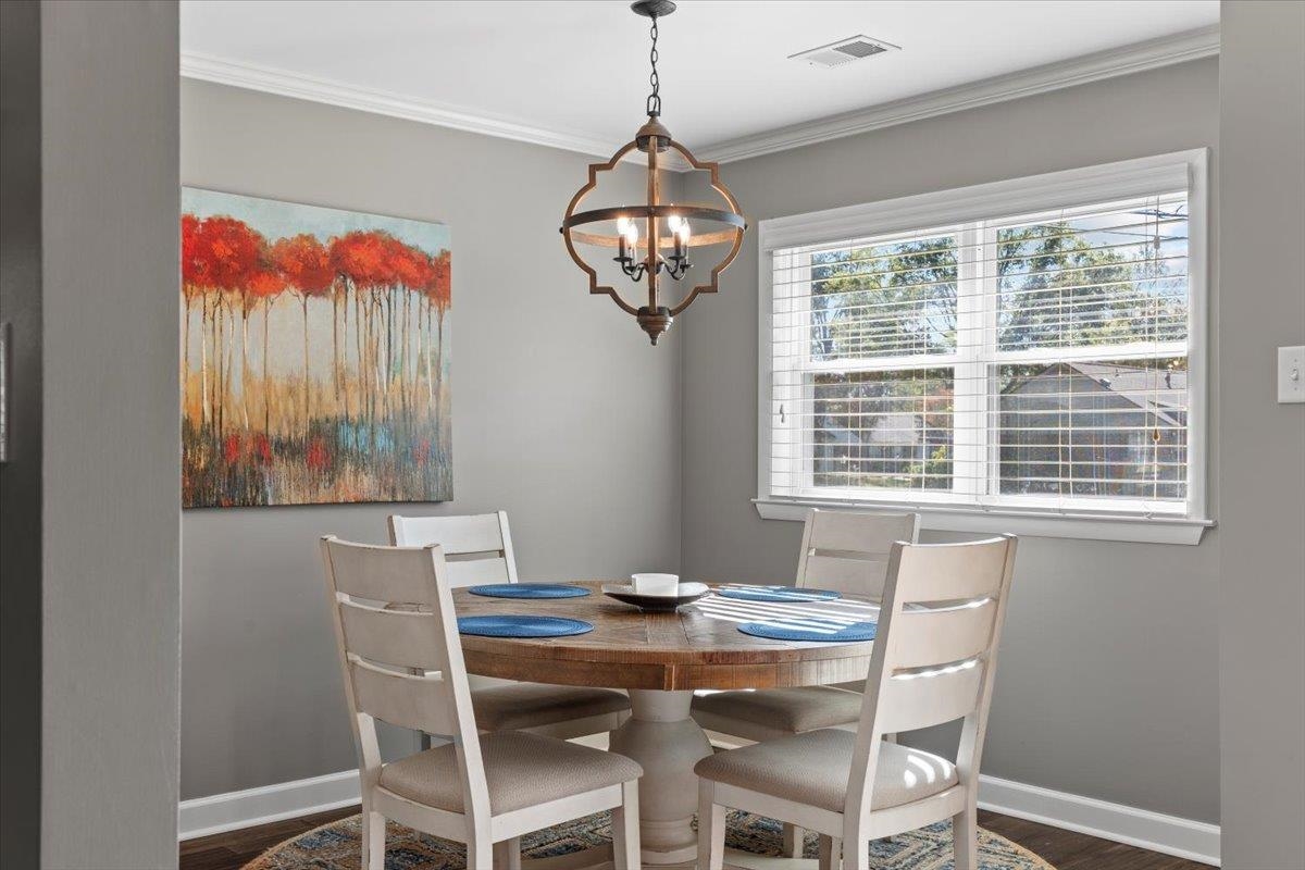 Dining room with a notable chandelier, dark hardwood / wood-style flooring, and crown molding