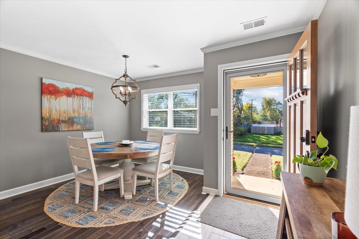 Dining area featuring dark hardwood / wood-style floors, crown molding, and a chandelier