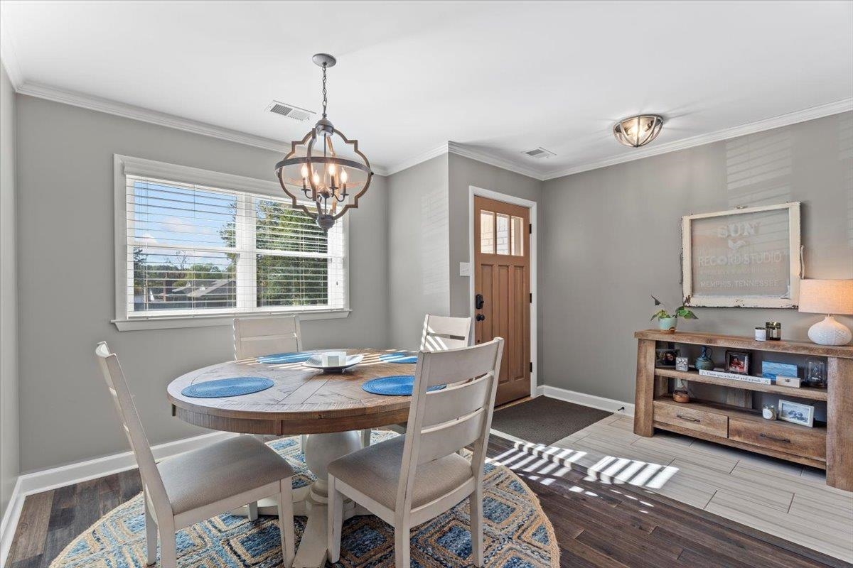 Dining room featuring a chandelier, crown molding, and wood-type flooring