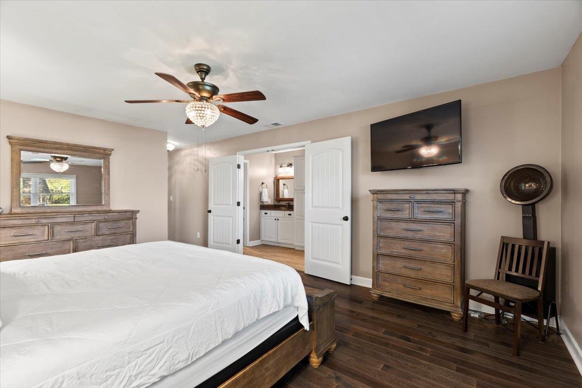 Bedroom featuring ceiling fan, ensuite bathroom, and dark wood-type flooring