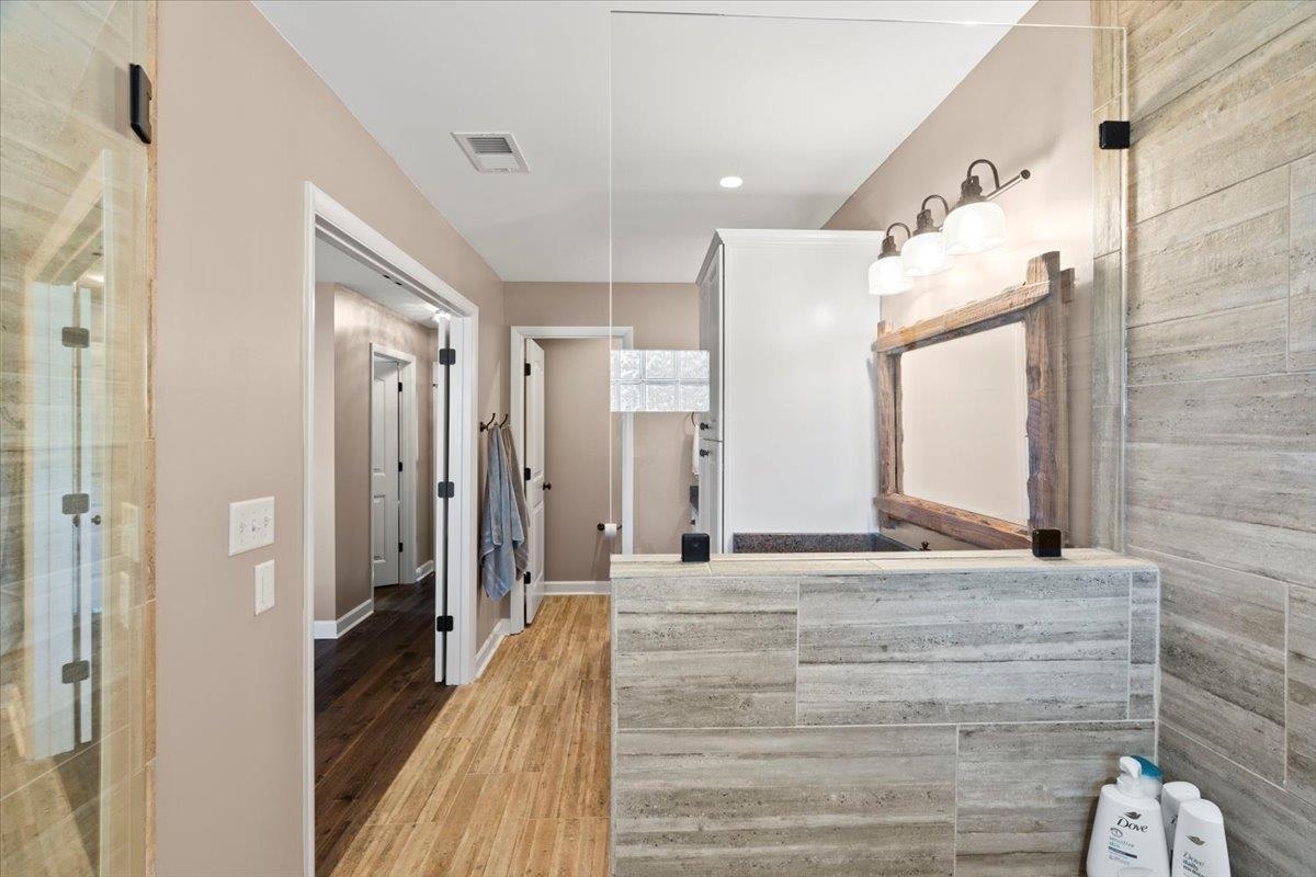 Bathroom with hardwood / wood-style flooring and an enclosed shower