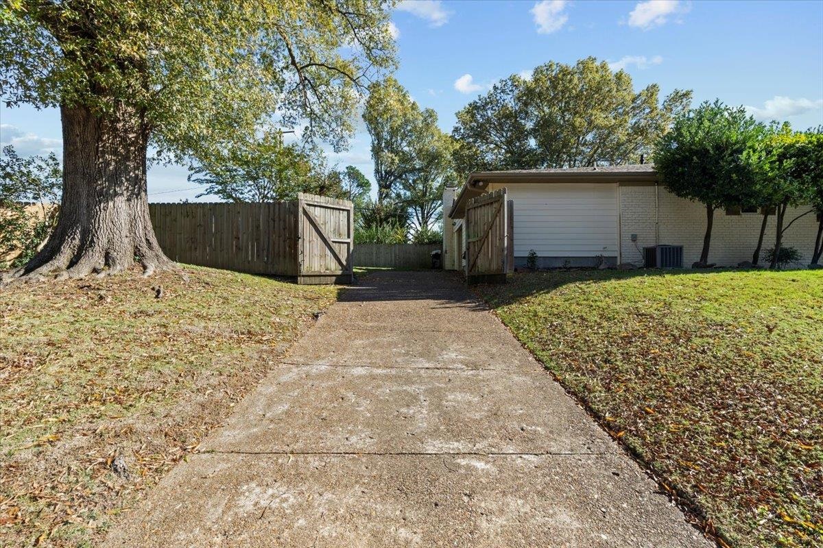 View of side of property with a lawn and central AC unit