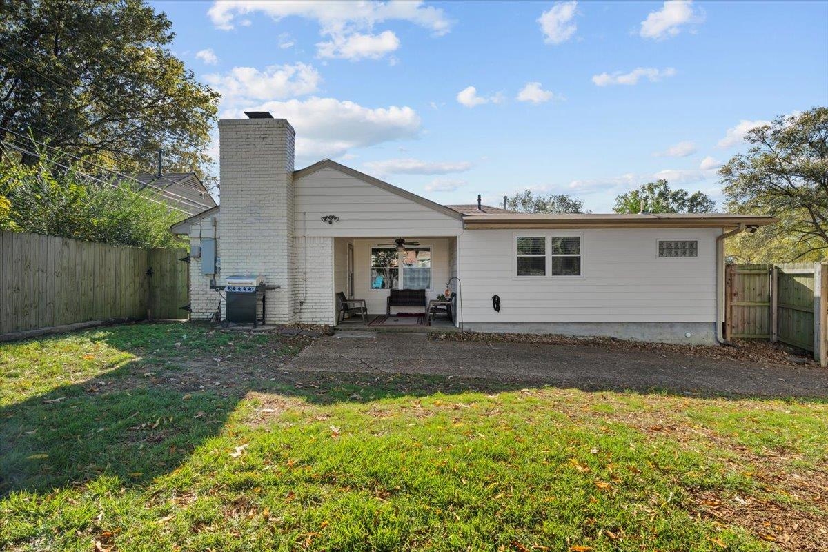 Rear view of property with a lawn, ceiling fan, and a patio