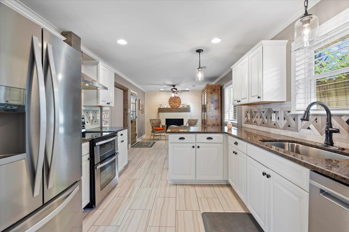 Kitchen featuring hanging light fixtures, white cabinetry, sink, and appliances with stainless steel finishes