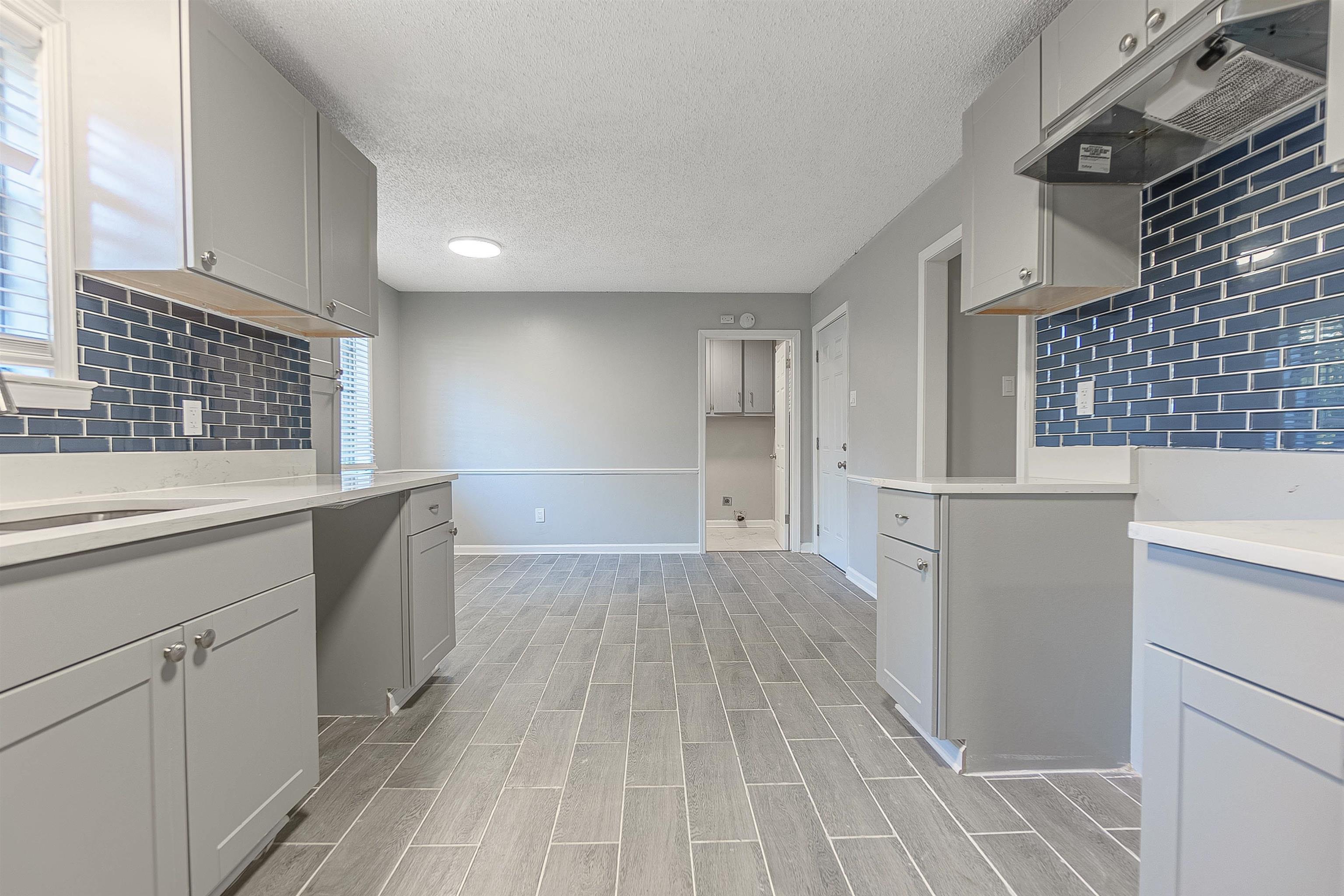 Kitchen featuring gray cabinets, light hardwood / wood-style flooring, a healthy amount of sunlight, and a textured ceiling