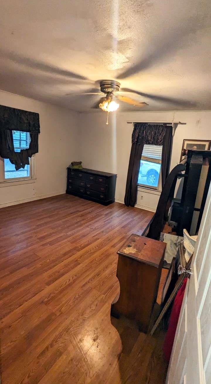 Interior space with hardwood / wood-style flooring, ceiling fan, and a textured ceiling