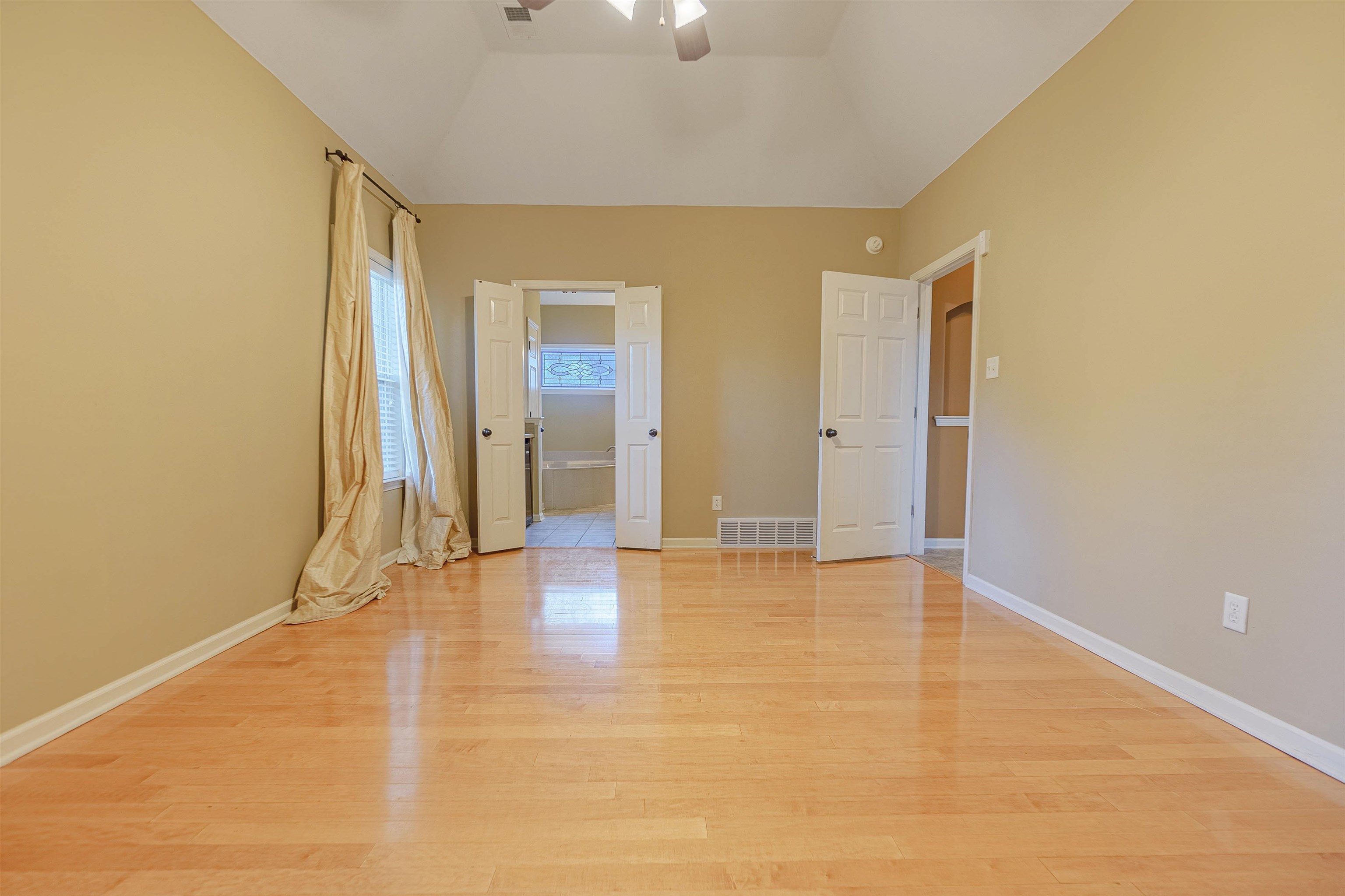 Unfurnished bedroom with ceiling fan, light wood-type flooring, and lofted ceiling