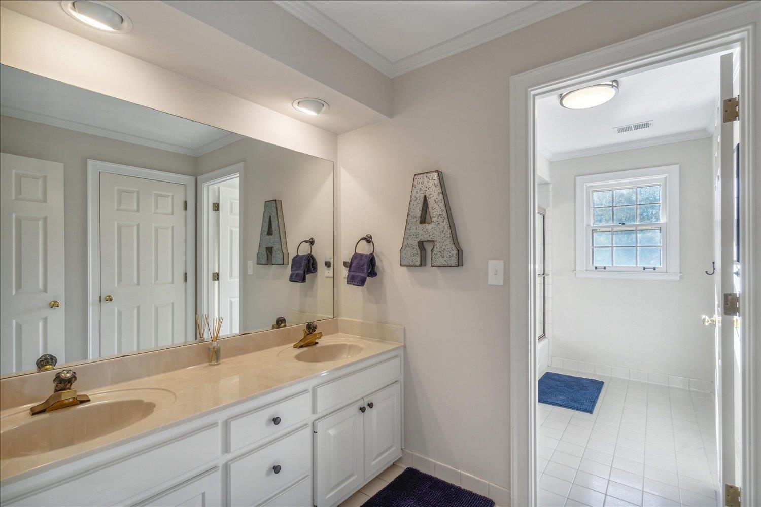 Bathroom with crown molding, tile patterned flooring, and vanity