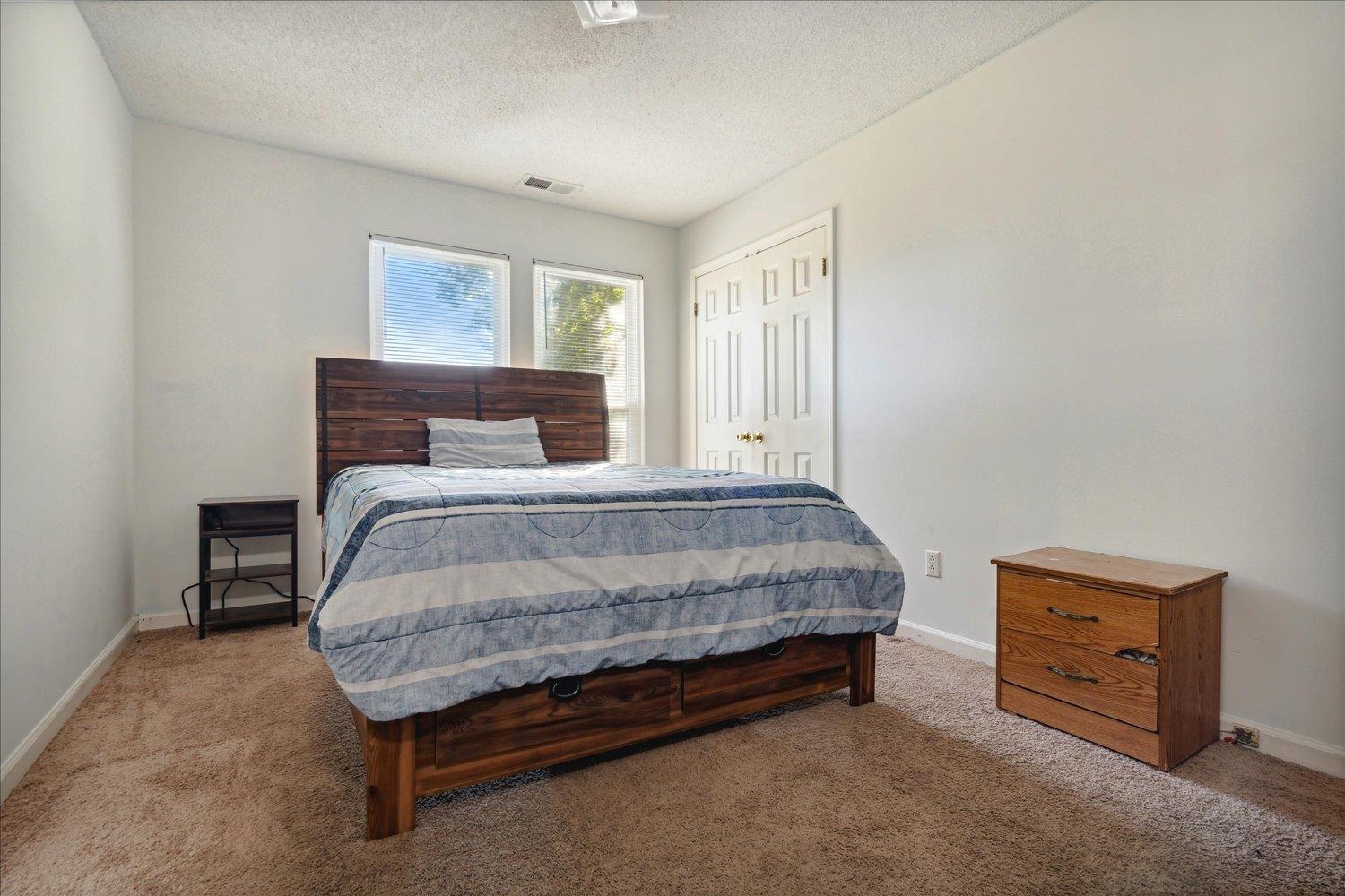 Carpeted bedroom featuring a textured ceiling and a closet