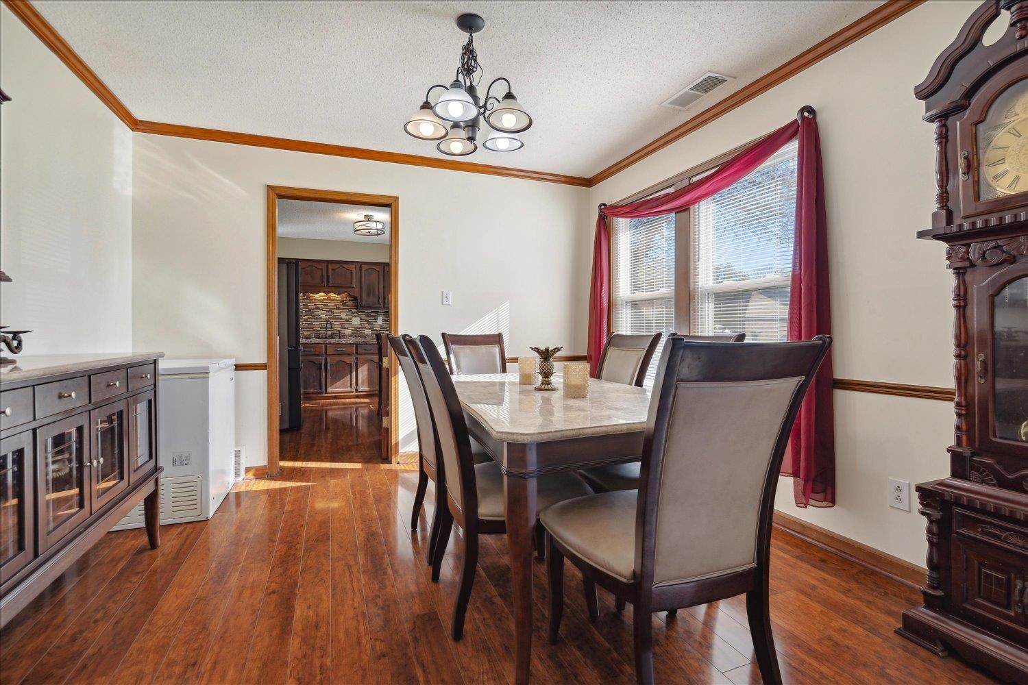 Dining room with a chandelier, a textured ceiling, dark hardwood / wood-style flooring, and crown molding