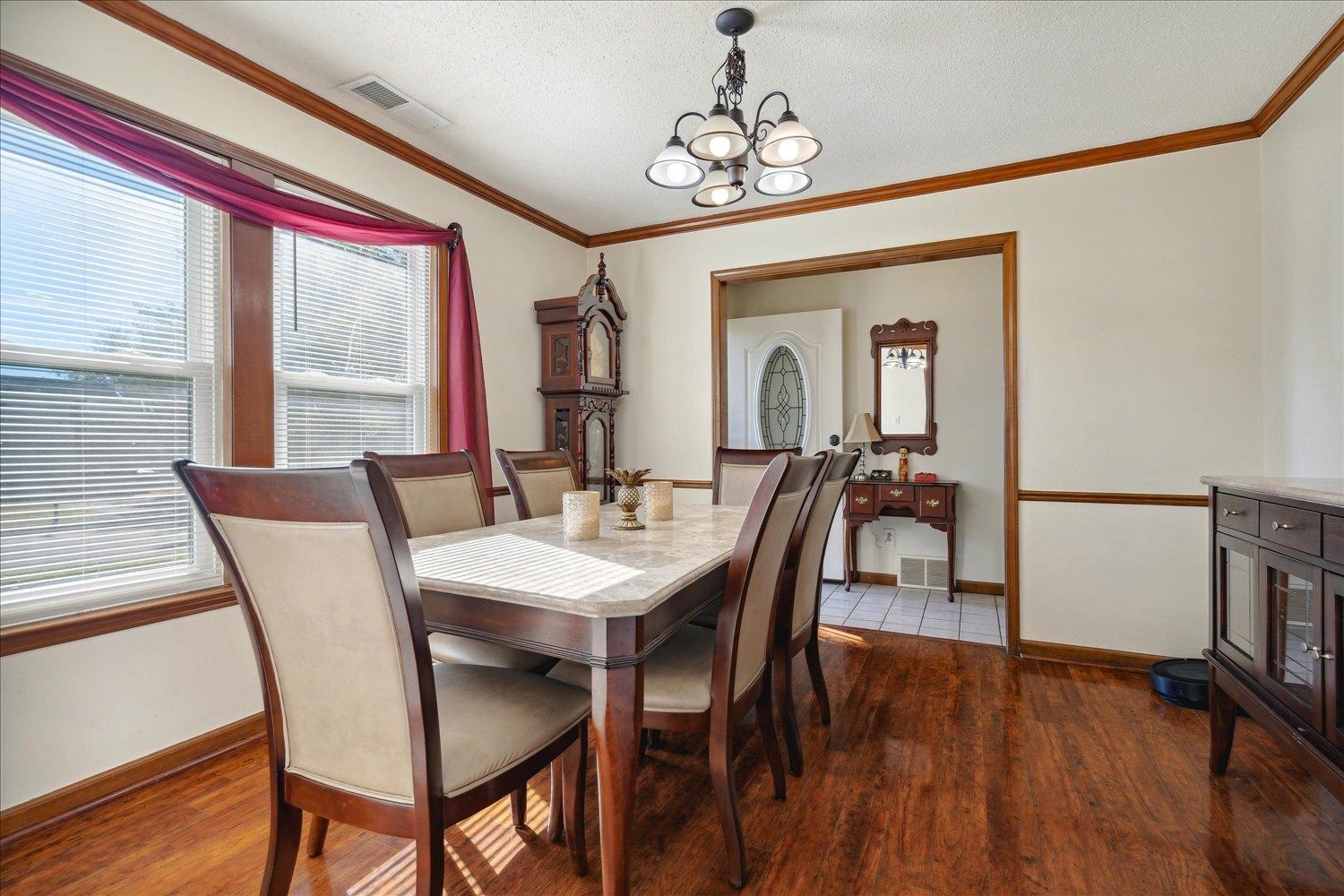 Dining room featuring crown molding, dark hardwood / wood-style flooring, a textured ceiling, and a notable chandelier