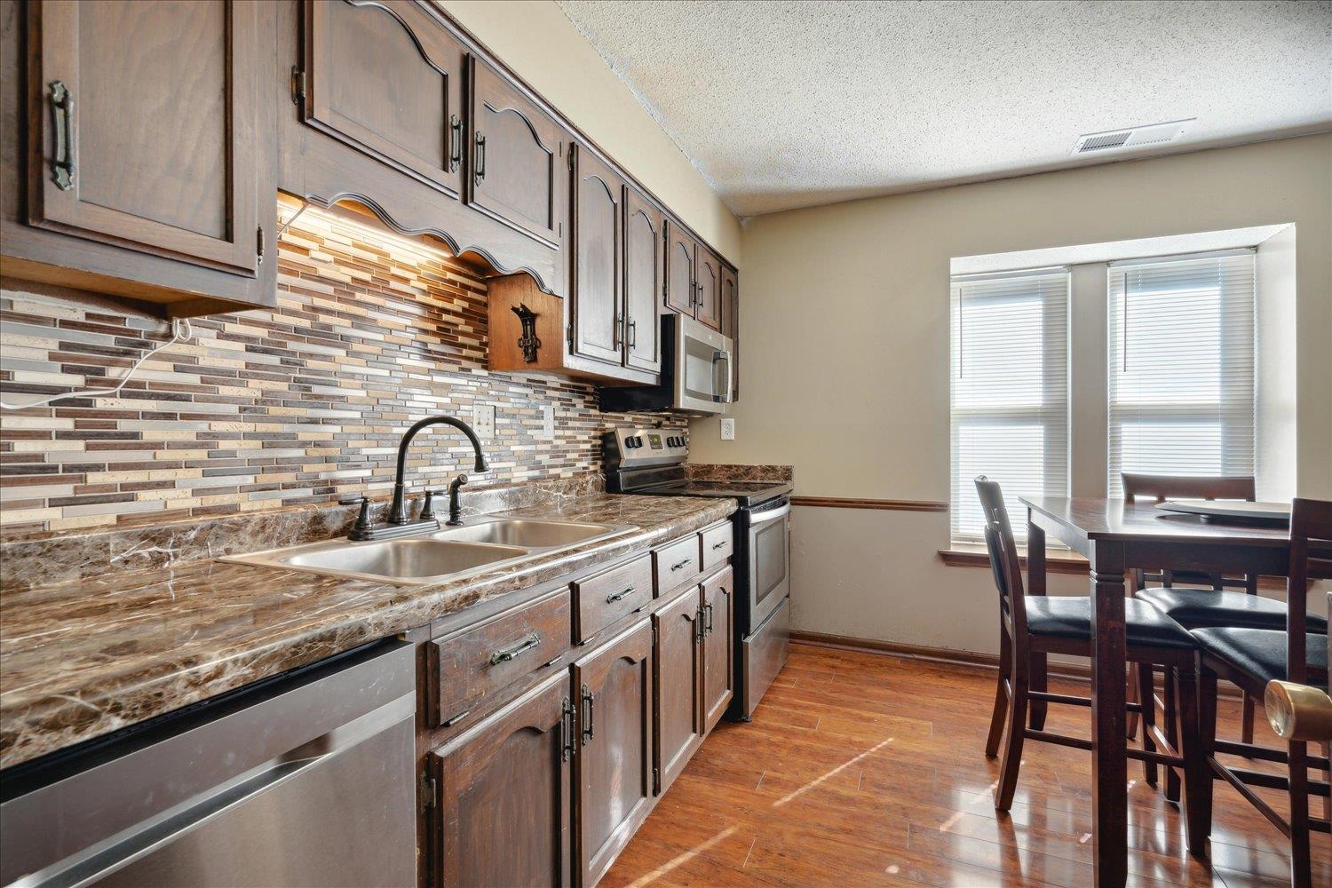 Kitchen featuring sink, light hardwood / wood-style floors, a textured ceiling, and appliances with stainless steel finishes