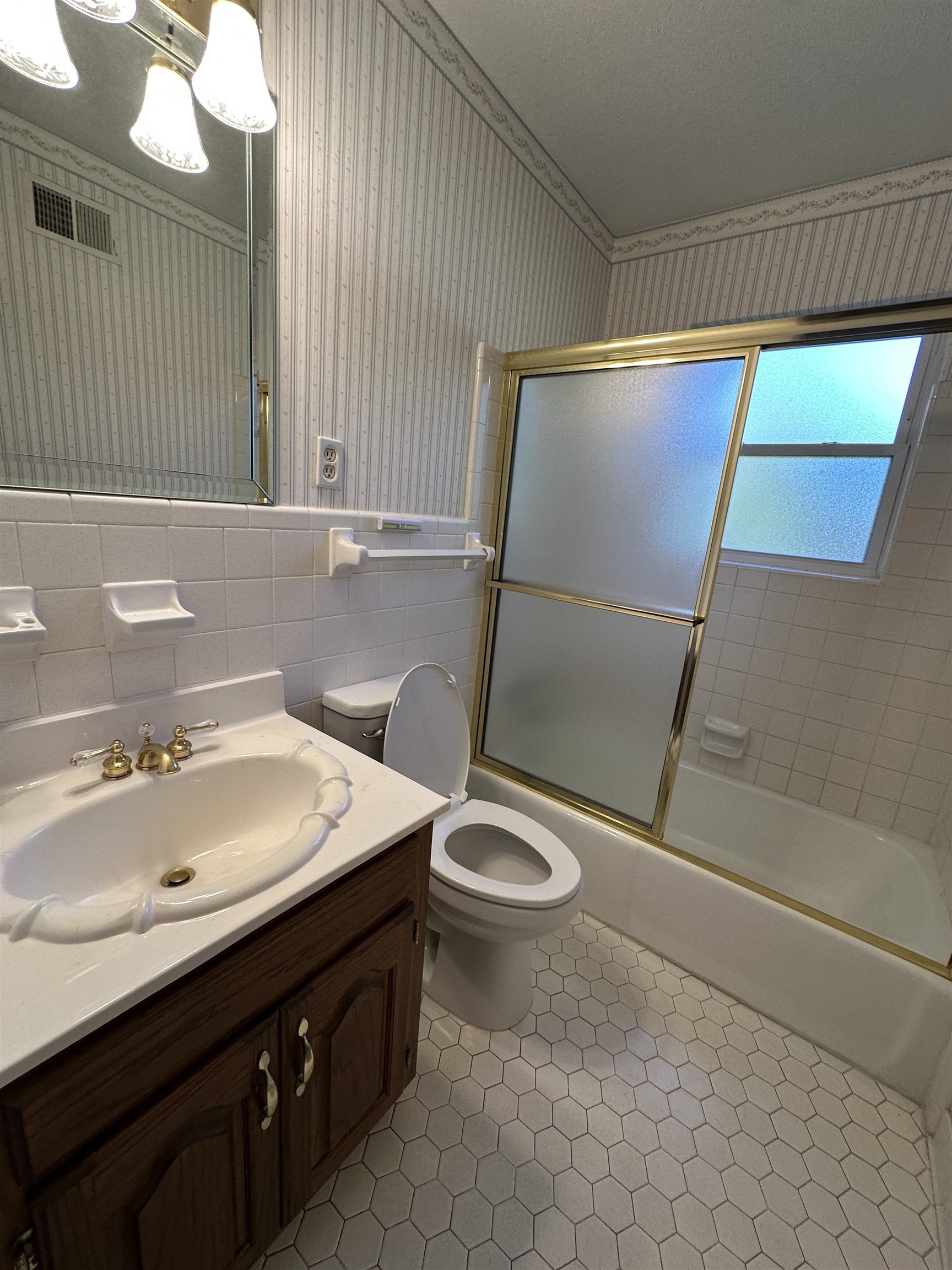 Full bathroom featuring tile patterned floors, bath / shower combo with glass door, vanity, tile walls, and toilet