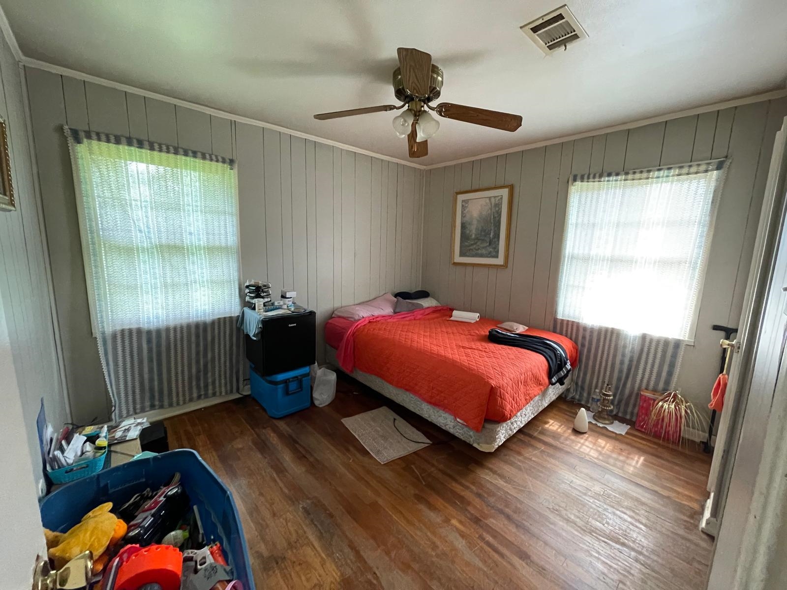 Bedroom featuring dark hardwood / wood-style flooring, ceiling fan, ornamental molding, and wood walls