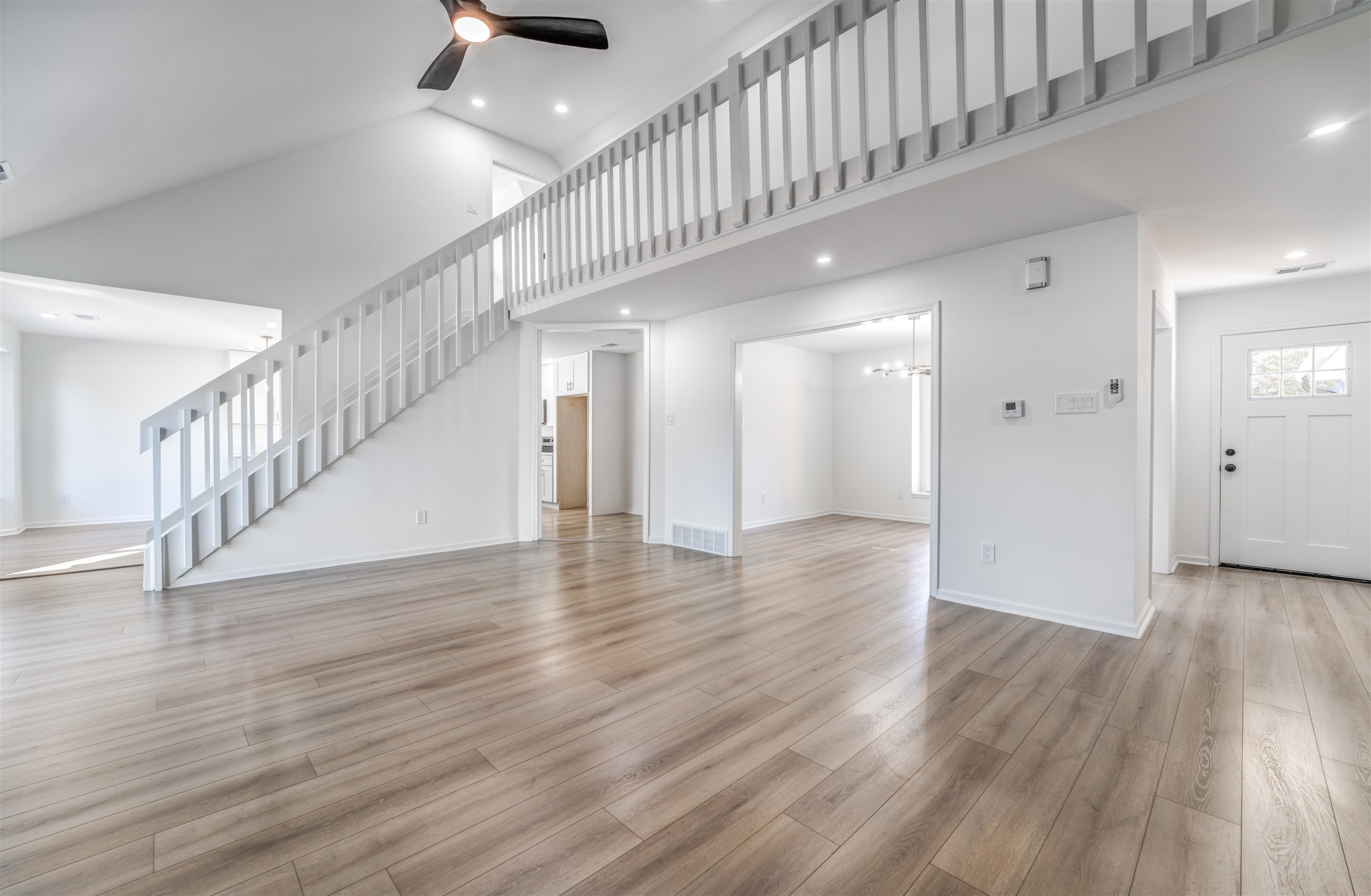 Unfurnished living room with light hardwood / wood-style floors, high vaulted ceiling, and ceiling fan