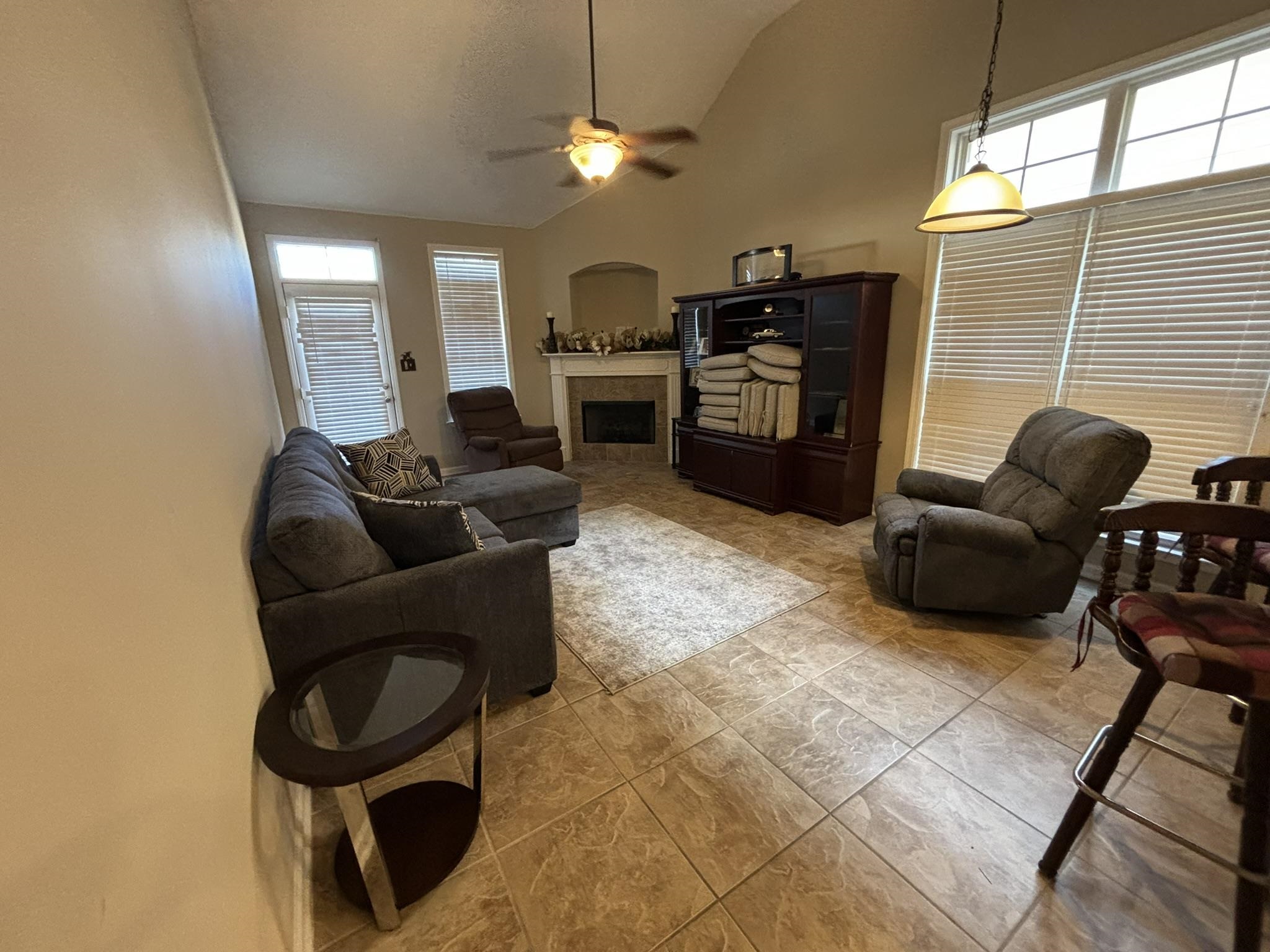 Hearth room with ceiling fan, high vaulted ceiling, and a tiled fireplace for entertaining family and friends.