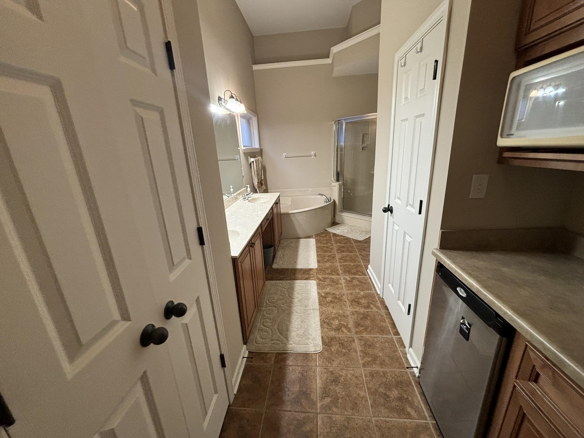 Bathroom featuring separate shower and tub, tile patterned flooring, and double vanity.