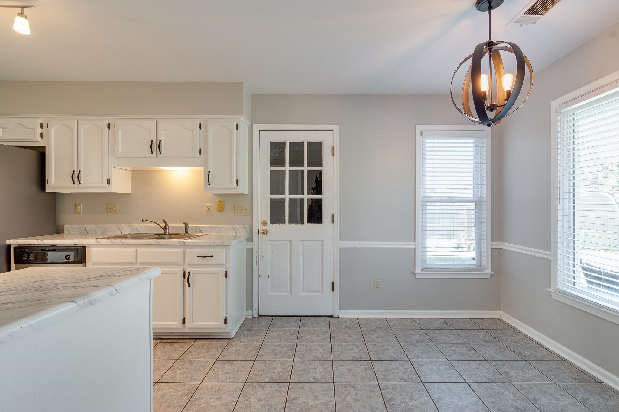 Kitchen with a wealth of natural light, white cabinetry, hanging light fixtures, and sink