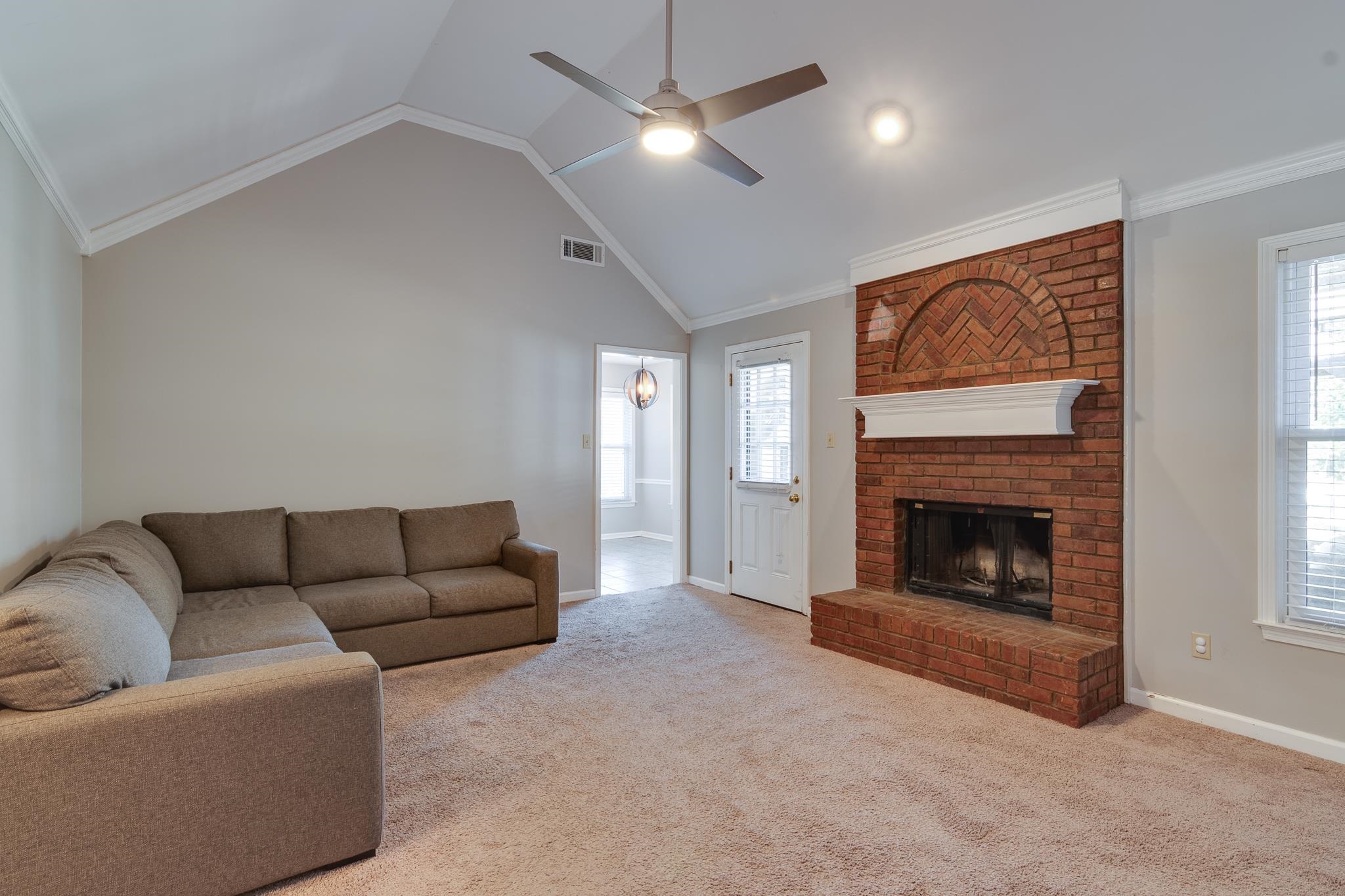 Living room featuring light colored carpet, ceiling fan, and crown molding