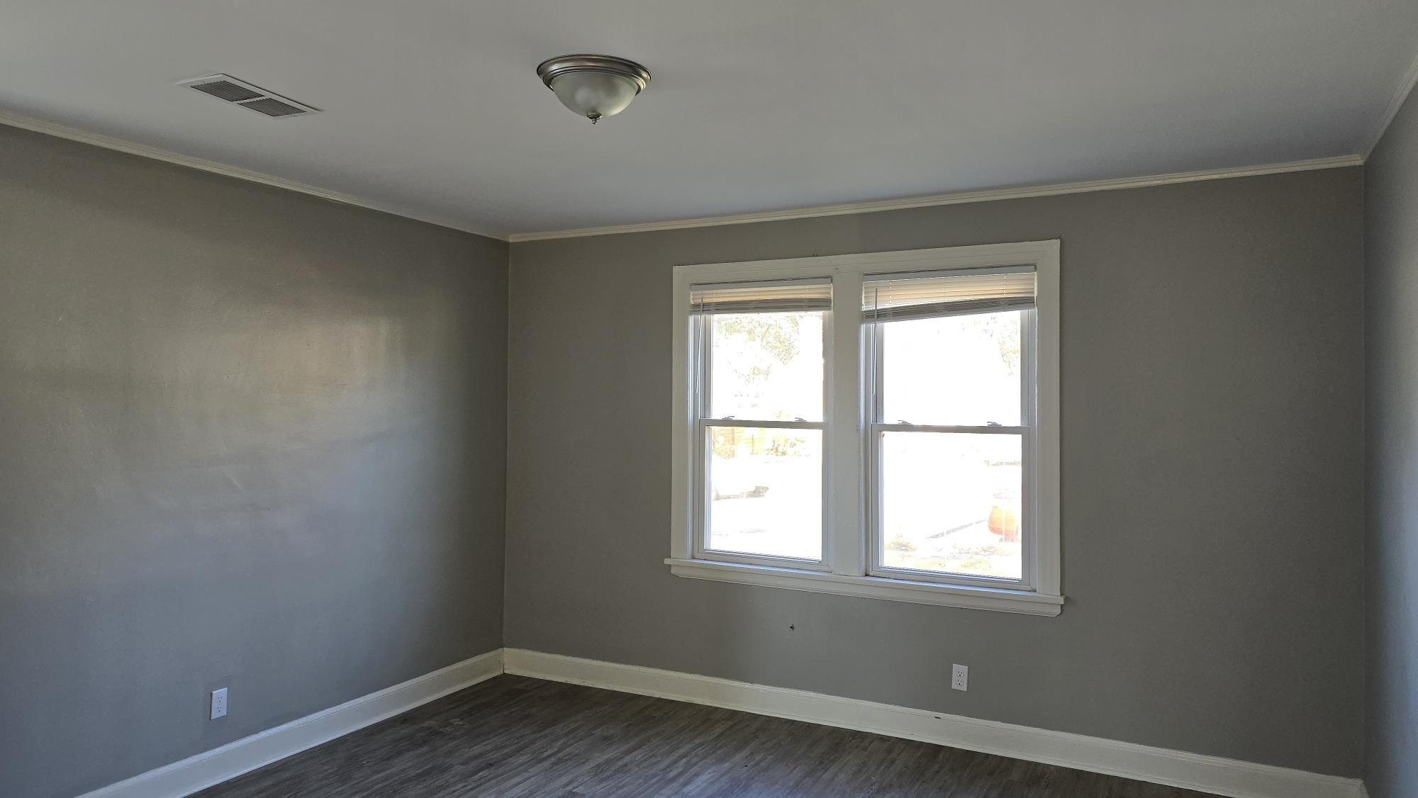 Unfurnished room with crown molding and dark wood-type flooring