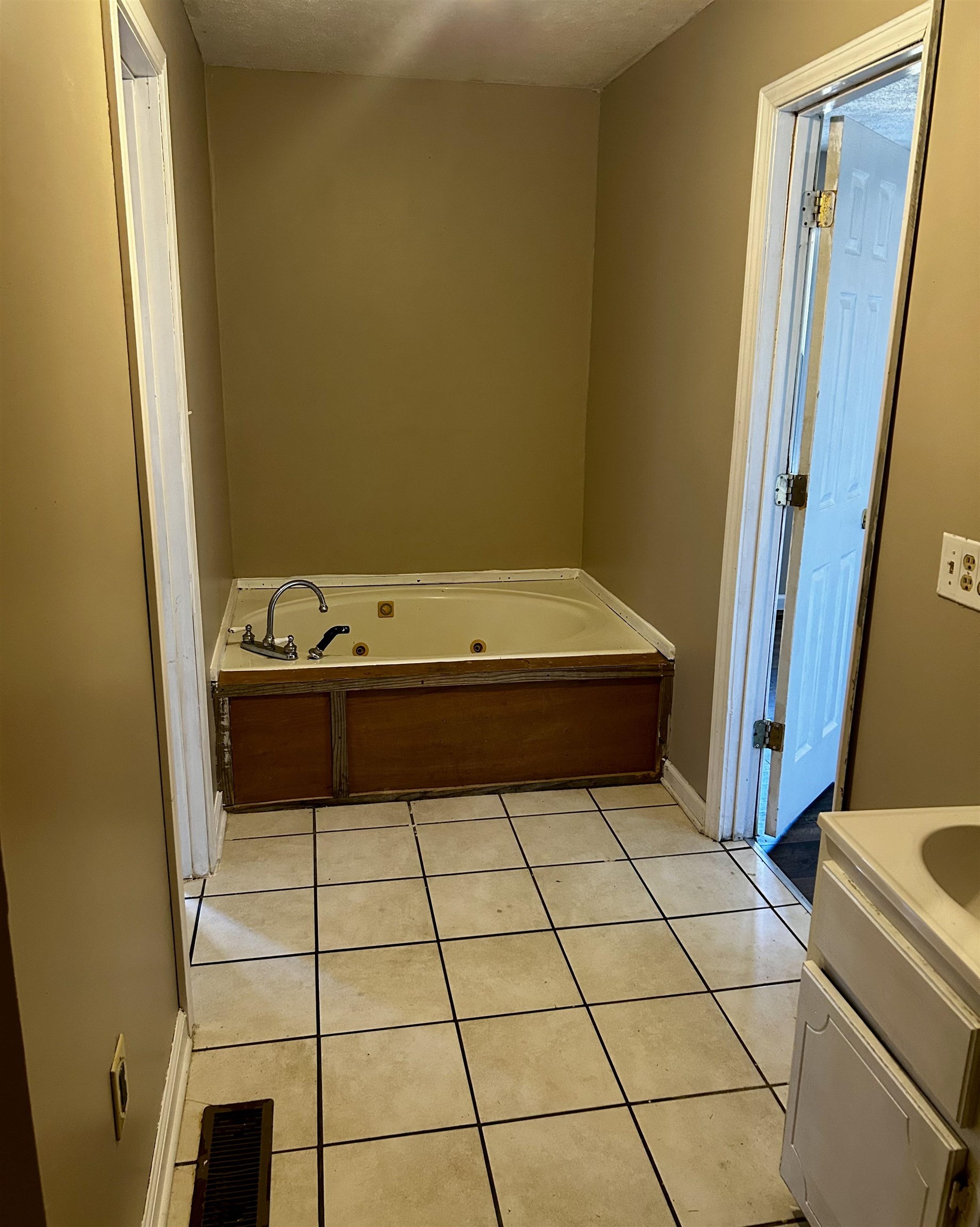 Bathroom featuring tile patterned floors, a bathtub, vanity, and a textured ceiling