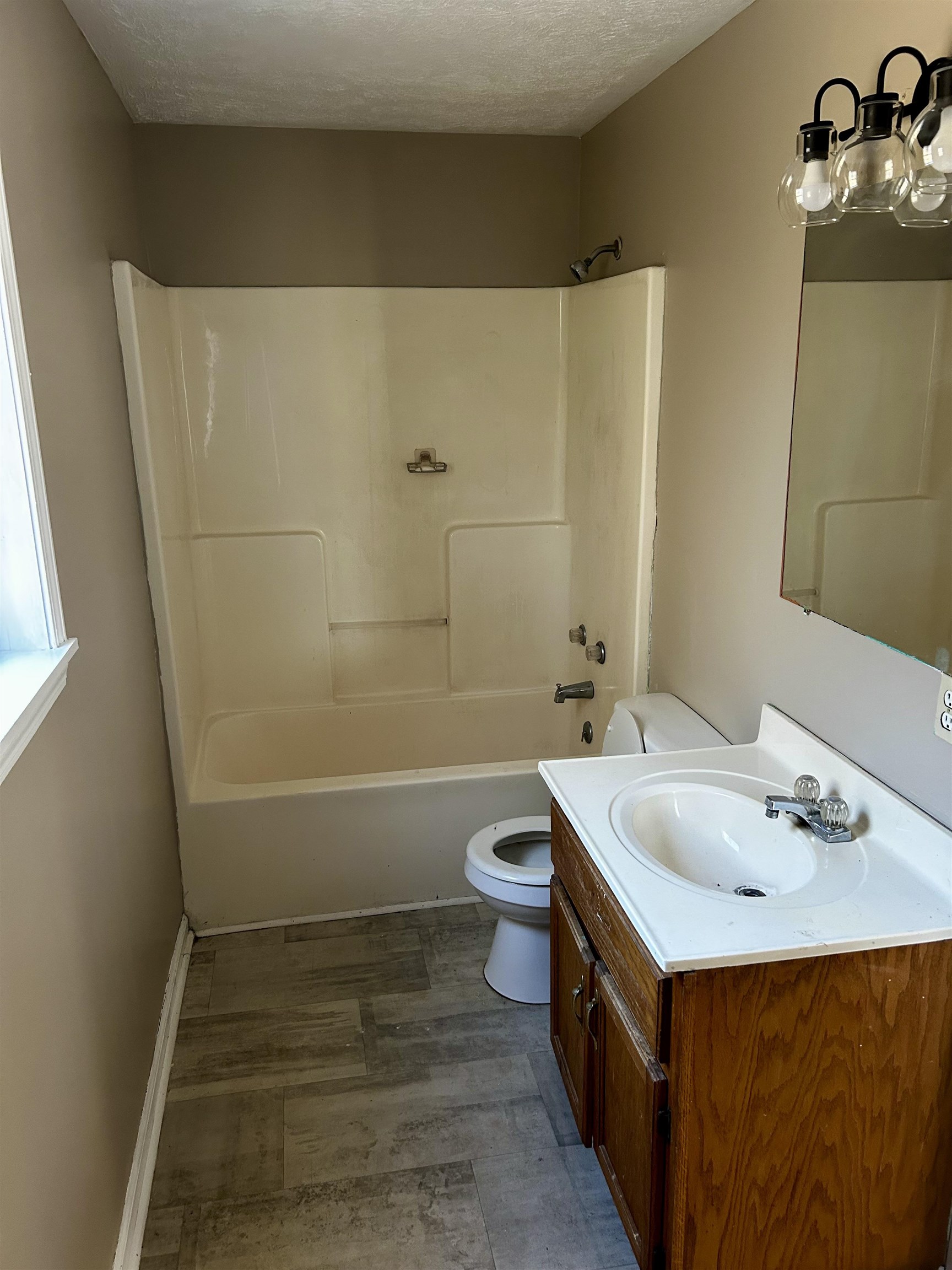 Full bathroom with washtub / shower combination, hardwood / wood-style floors, a textured ceiling, toilet, and vanity