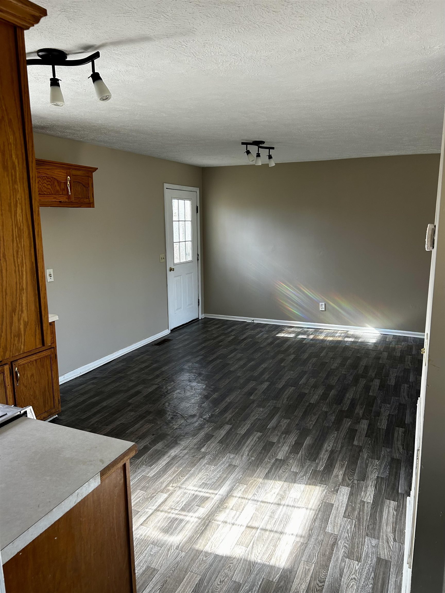 Interior space with a textured ceiling, dark hardwood / wood-style flooring, and rail lighting