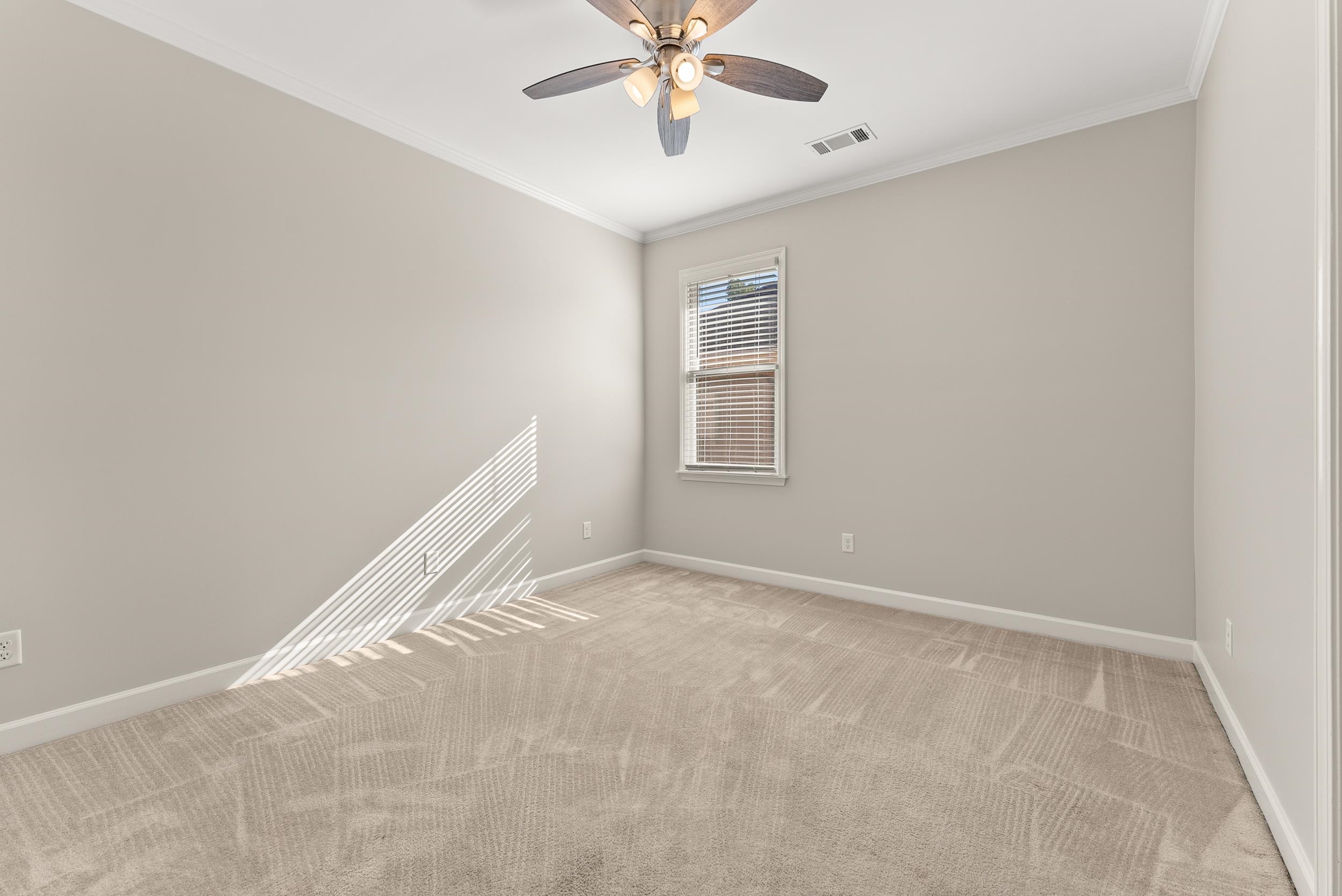 Unfurnished room with light colored carpet, ceiling fan, and ornamental molding