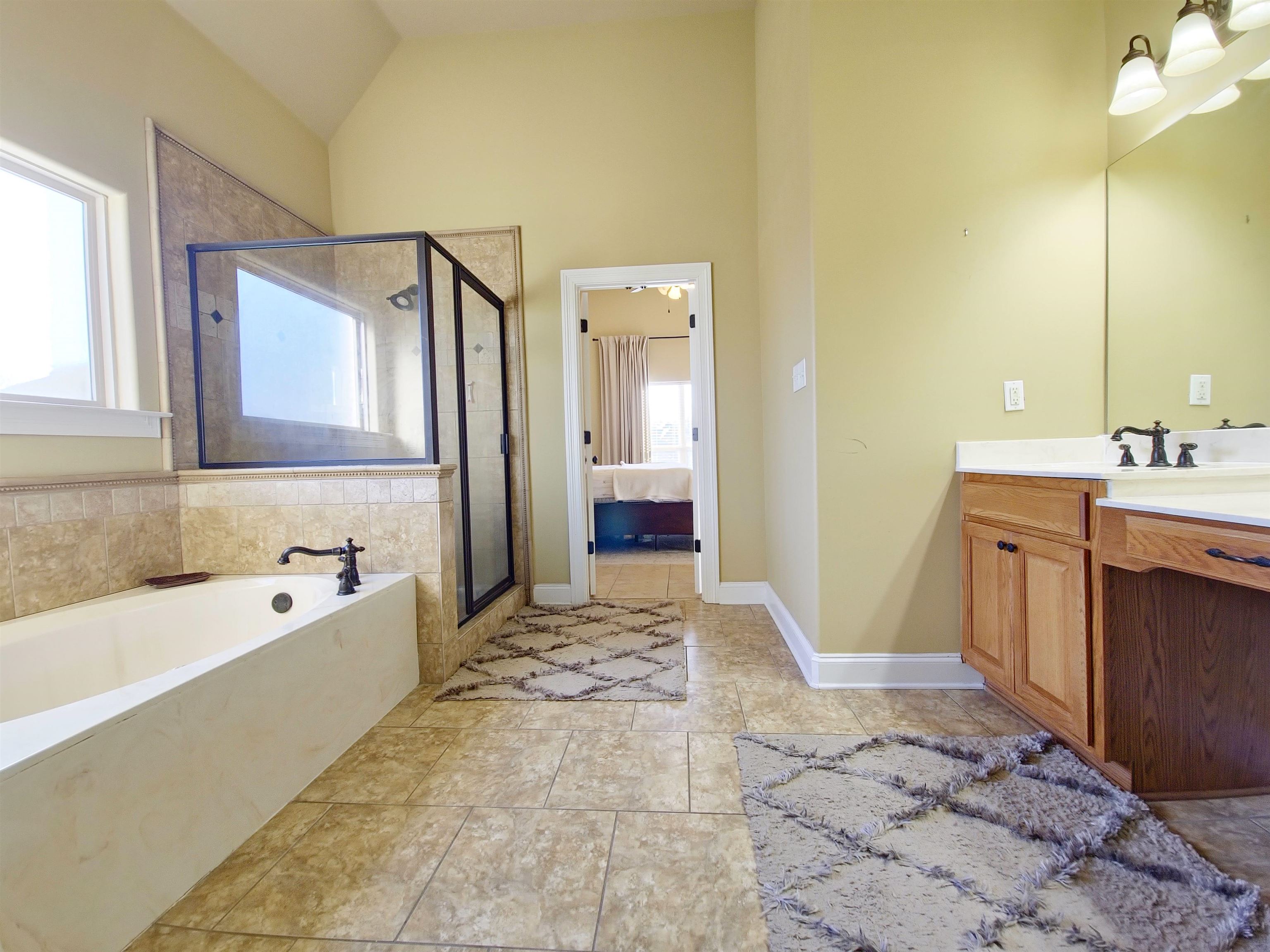 Bathroom with plus walk in shower, tile patterned flooring, vanity, and high vaulted ceiling