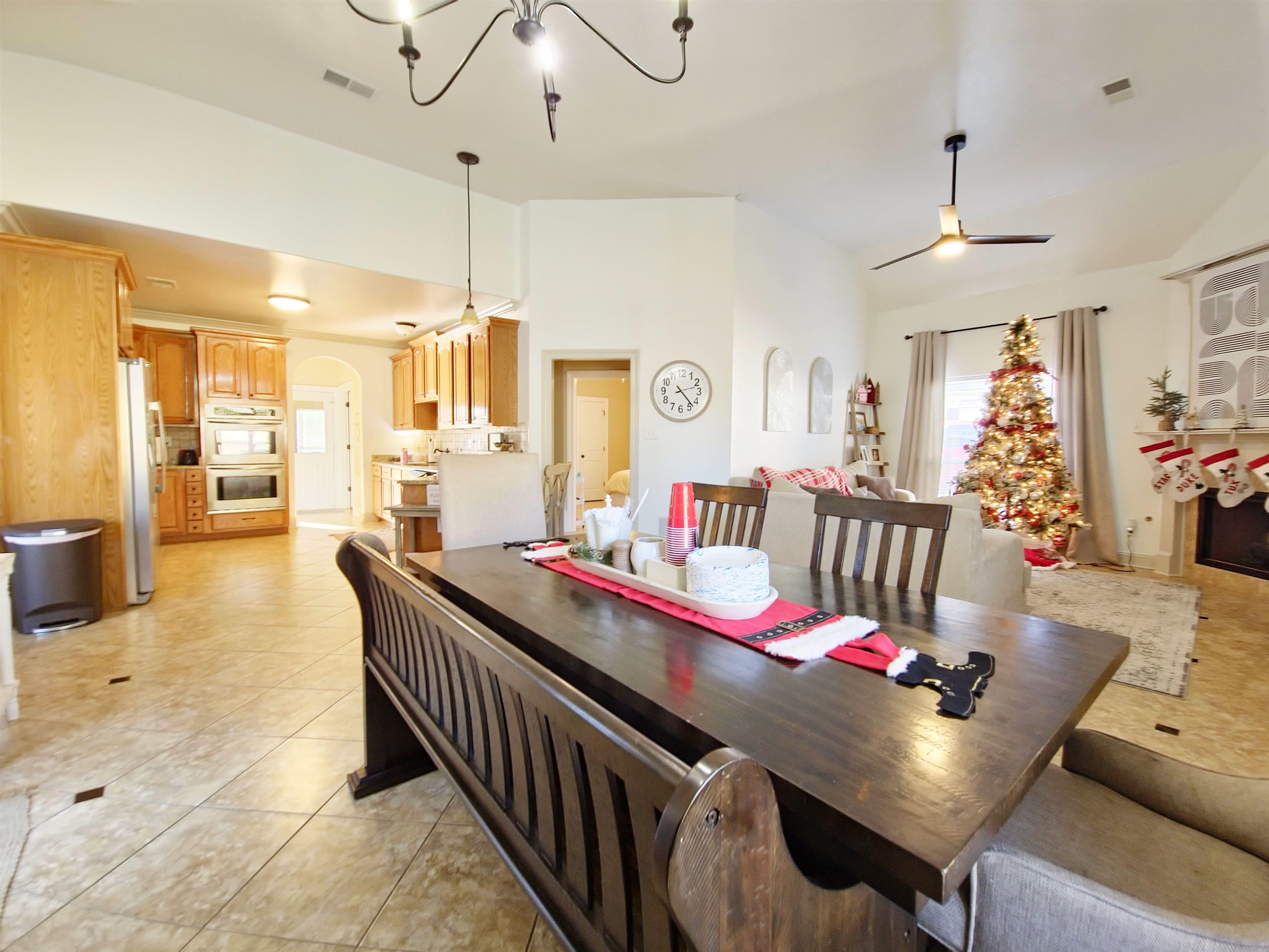 Tiled dining room with ceiling fan with notable chandelier