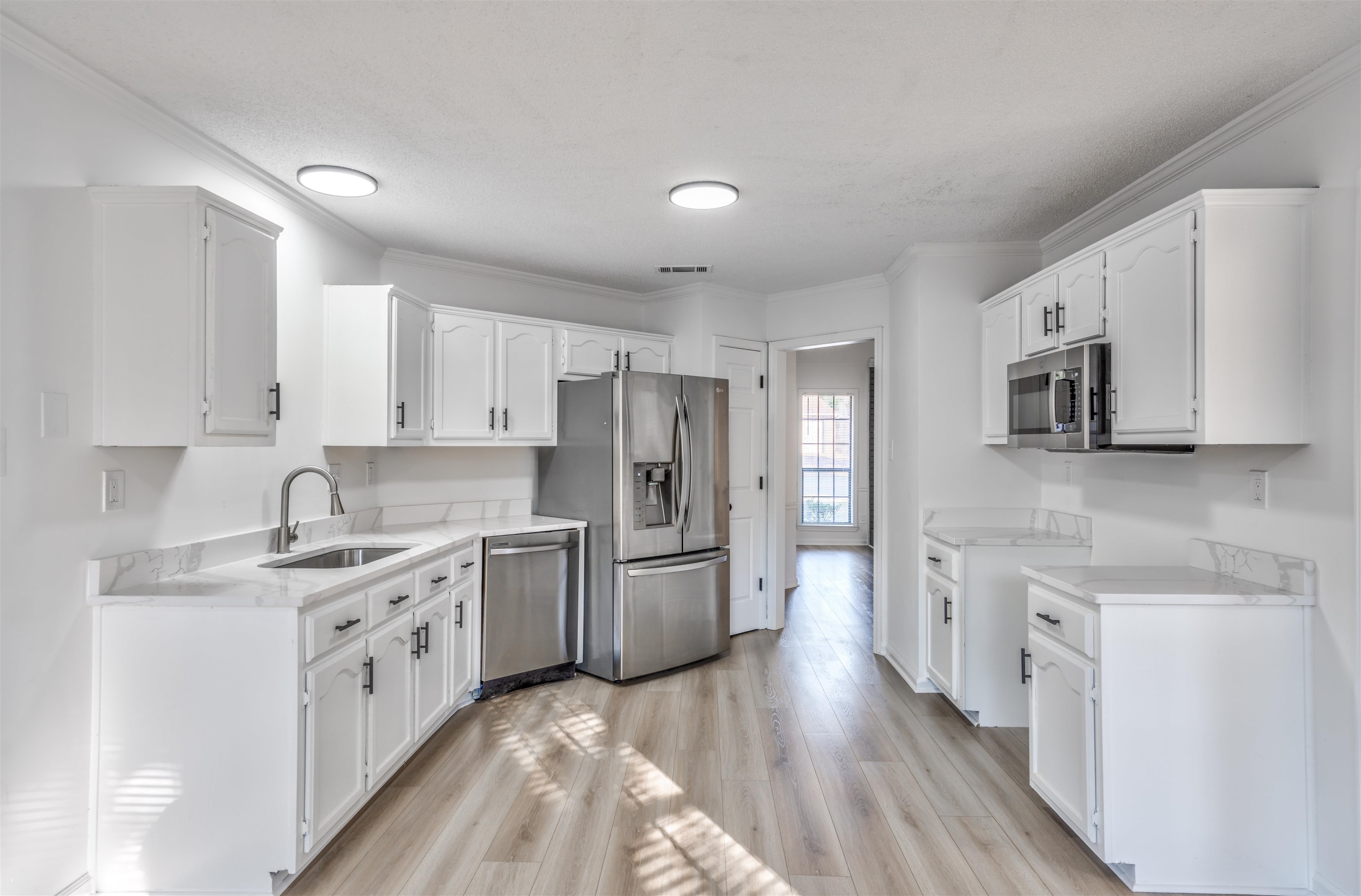 Kitchen featuring sink, white cabinetry, stainless steel appliances, and light hardwood / wood-style floors